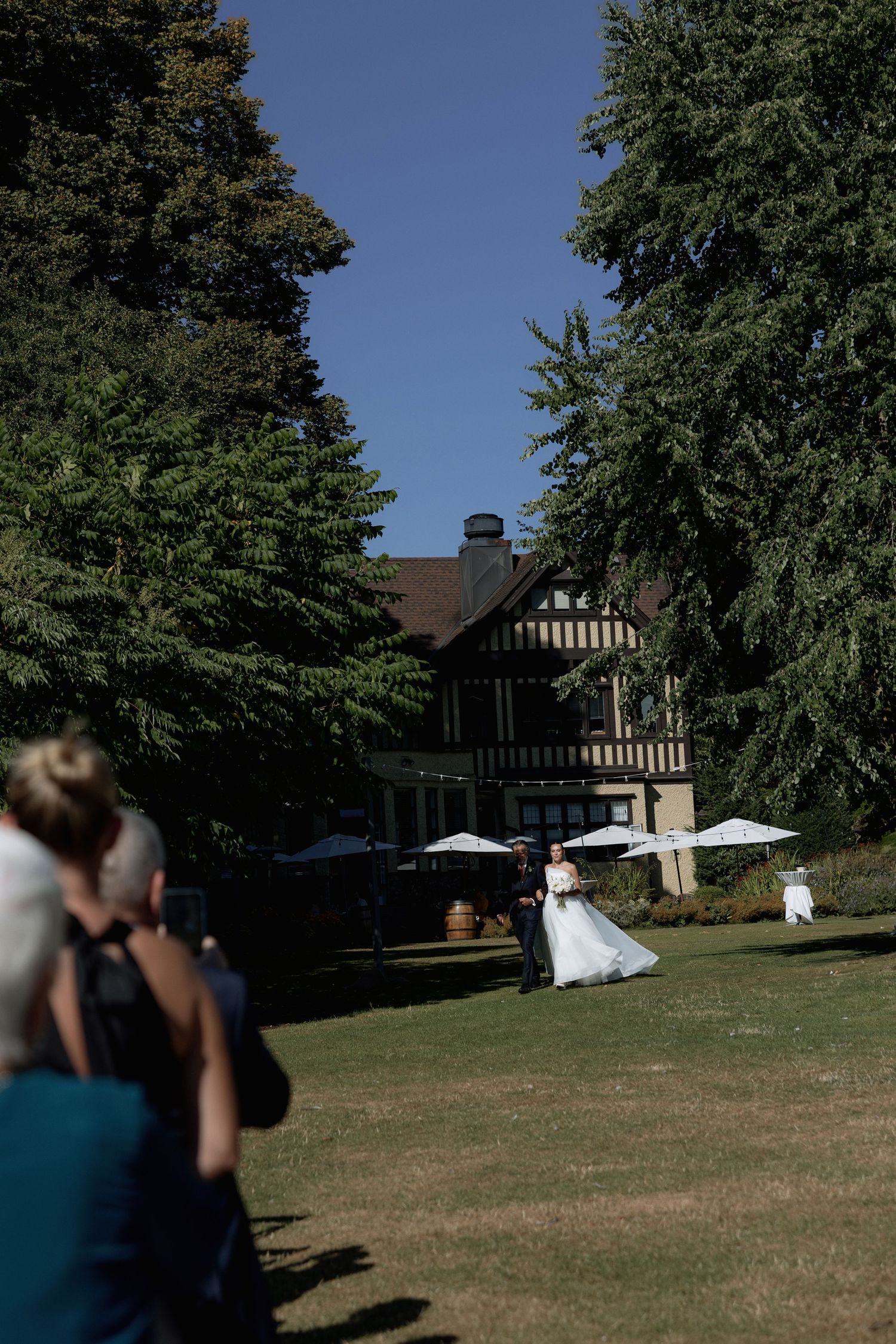 Wedding venue exterior showing a Tudor-style building with trees and a lawn ceremony setup at Hurt House in Burnaby