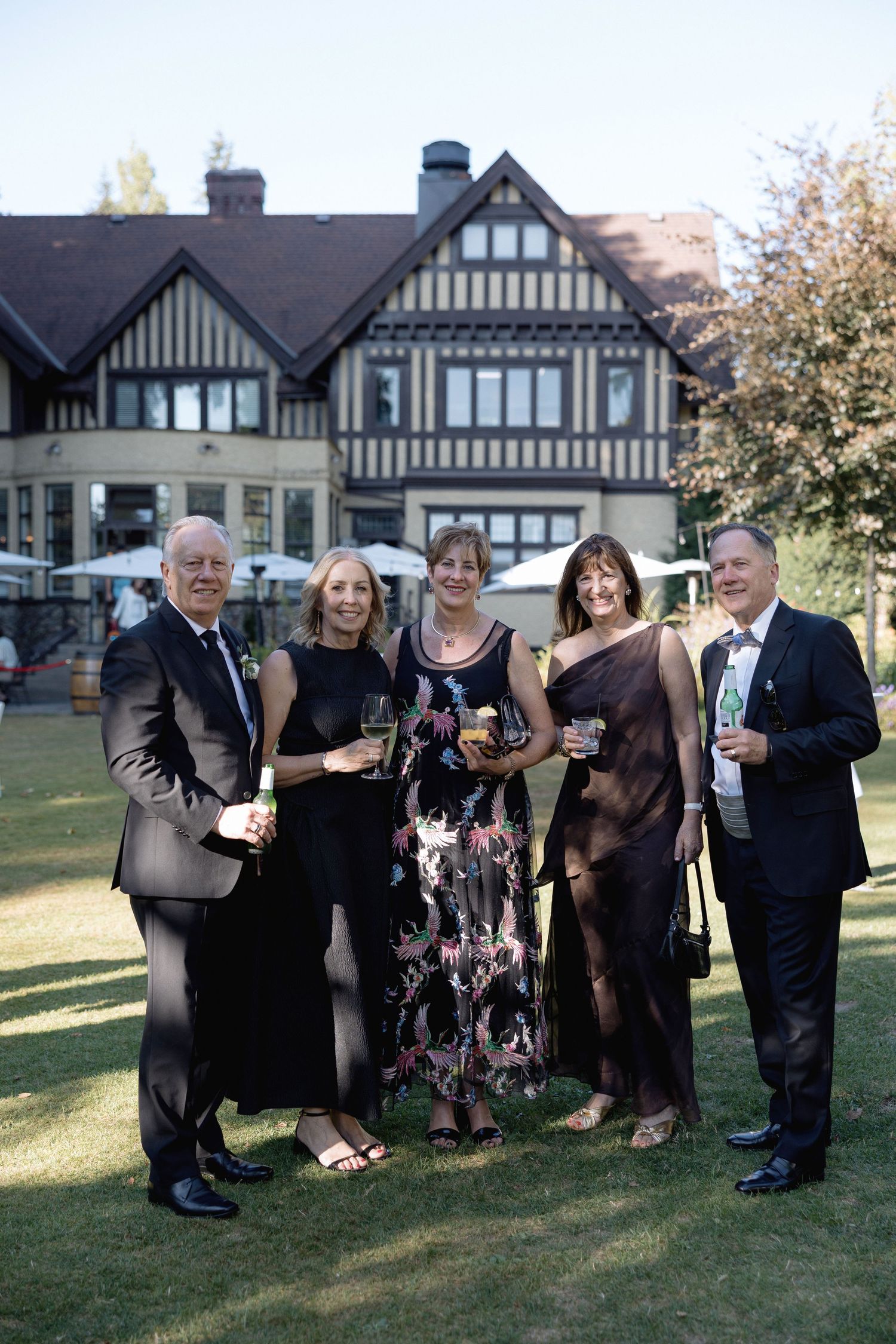 Group of wedding guests socializing on a lawn in front of a Hurt House in Burnaby.