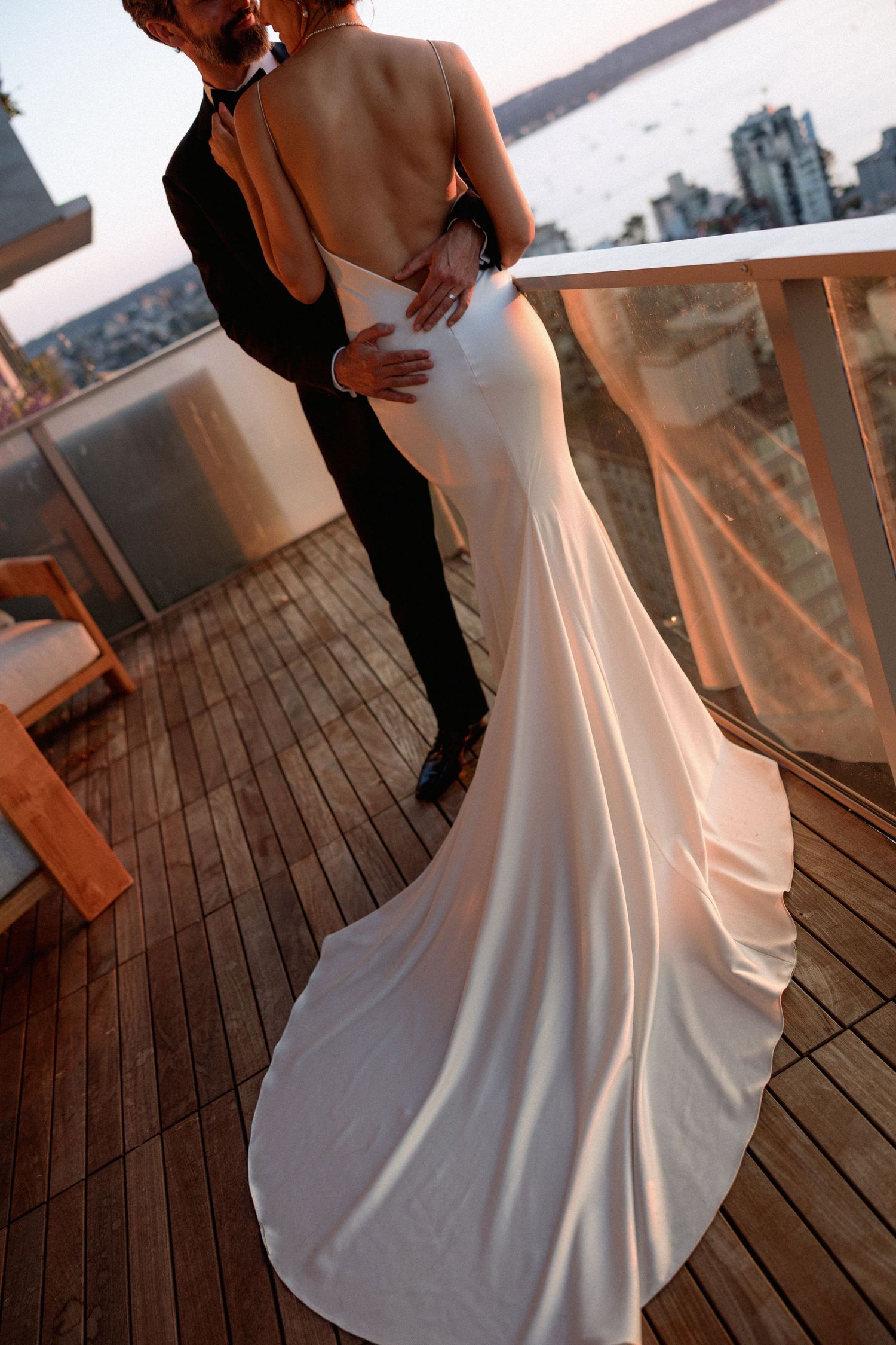 Couple dancing on wooden deck during sunset wedding reception.