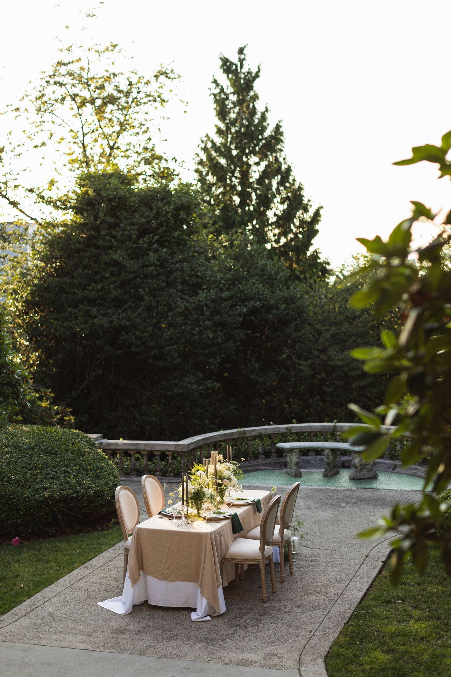 Outdoor dining setup with elegant table arrangements beside a swimming pool at sunset.
