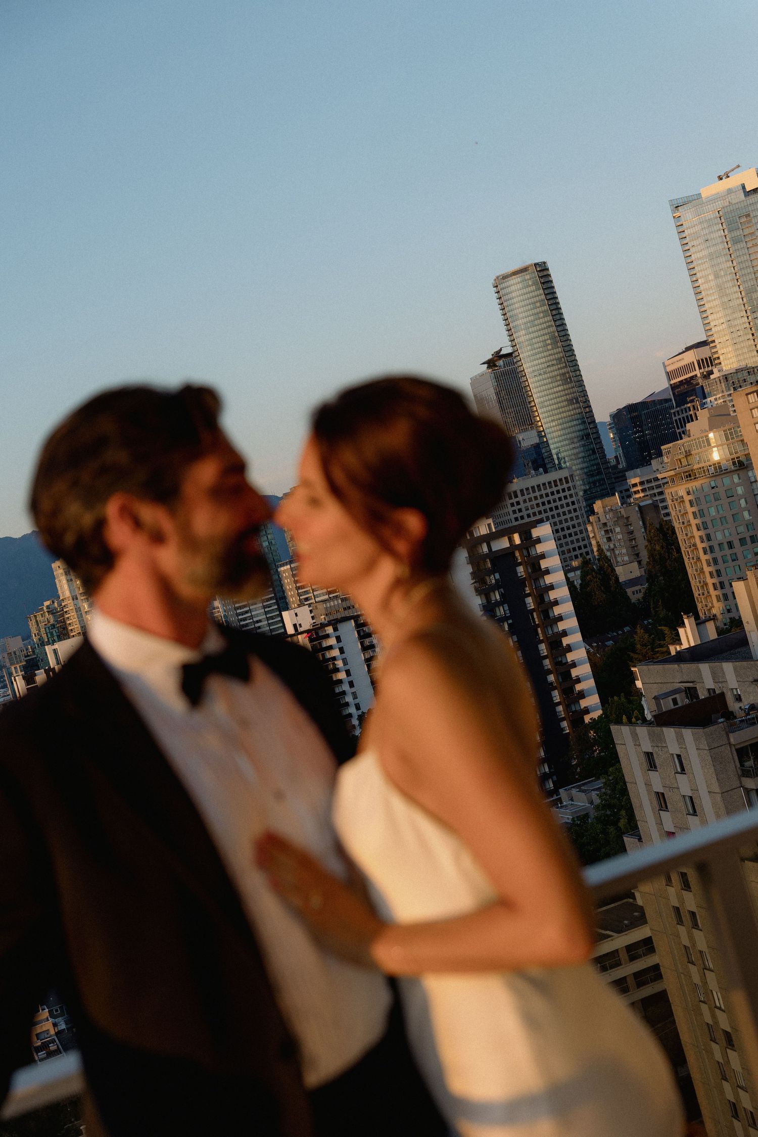 Silhouetted couple against Vancouver's downtown skyline during golden hour.