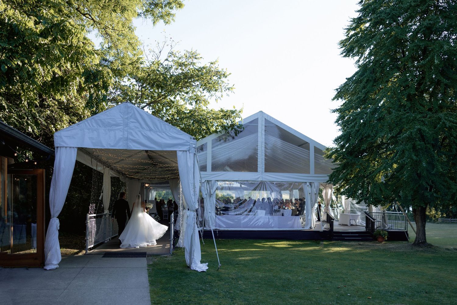 Wedding reception tent setup with white canopies and trees in outdoor venue Hurt House in Burnaby