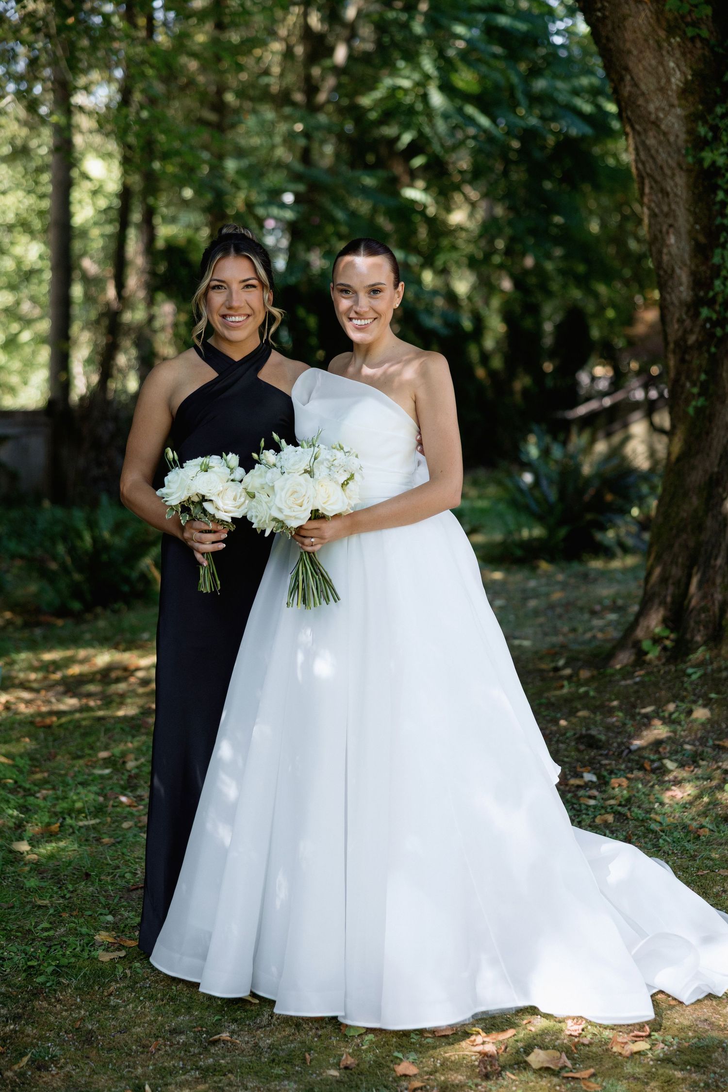 Wedding photo featuring two people in contrasting black and white dresses holding matching bouquets.