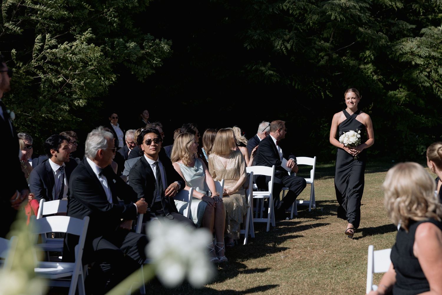 Outdoor wedding ceremony setup with white folding chairs and guests mingling before the event.