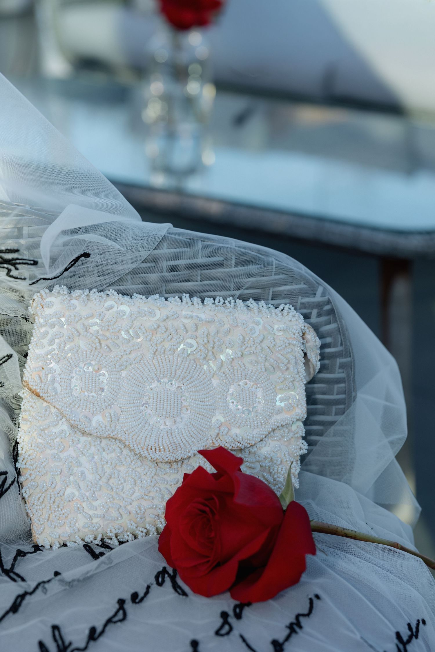 White lace bridal garter adorned with pearls and red roses on delicate tulle fabric.
