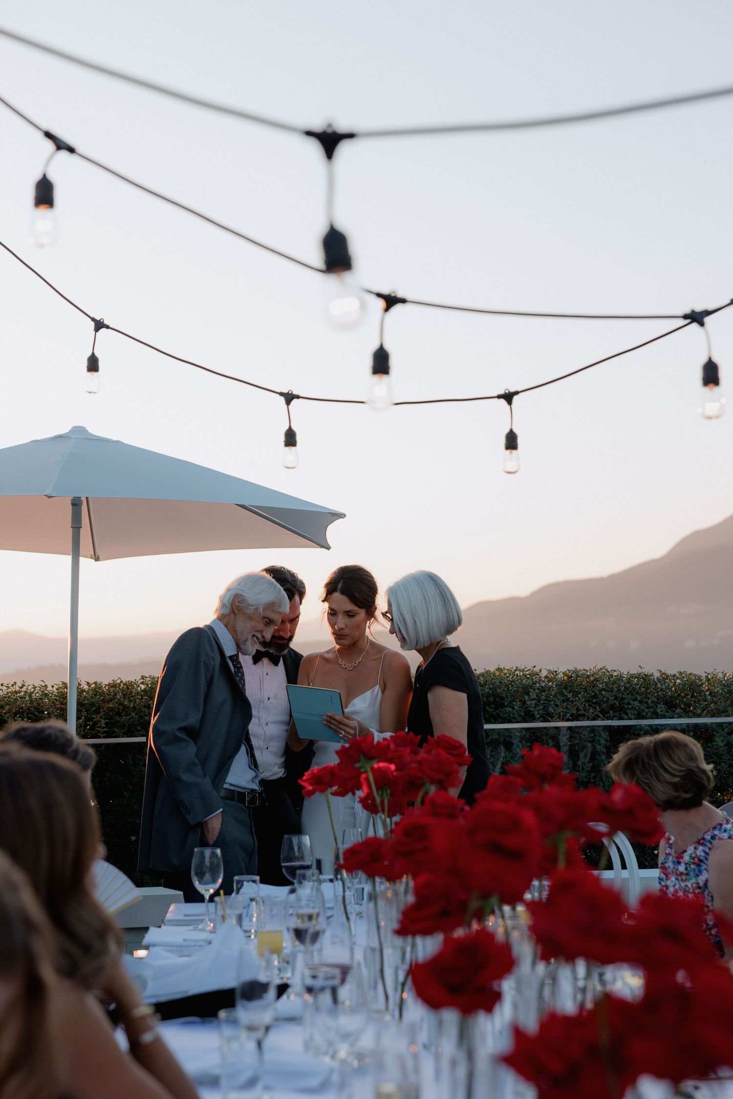 Intimate rooftop wedding reception with string lights and mountain views at sunset.