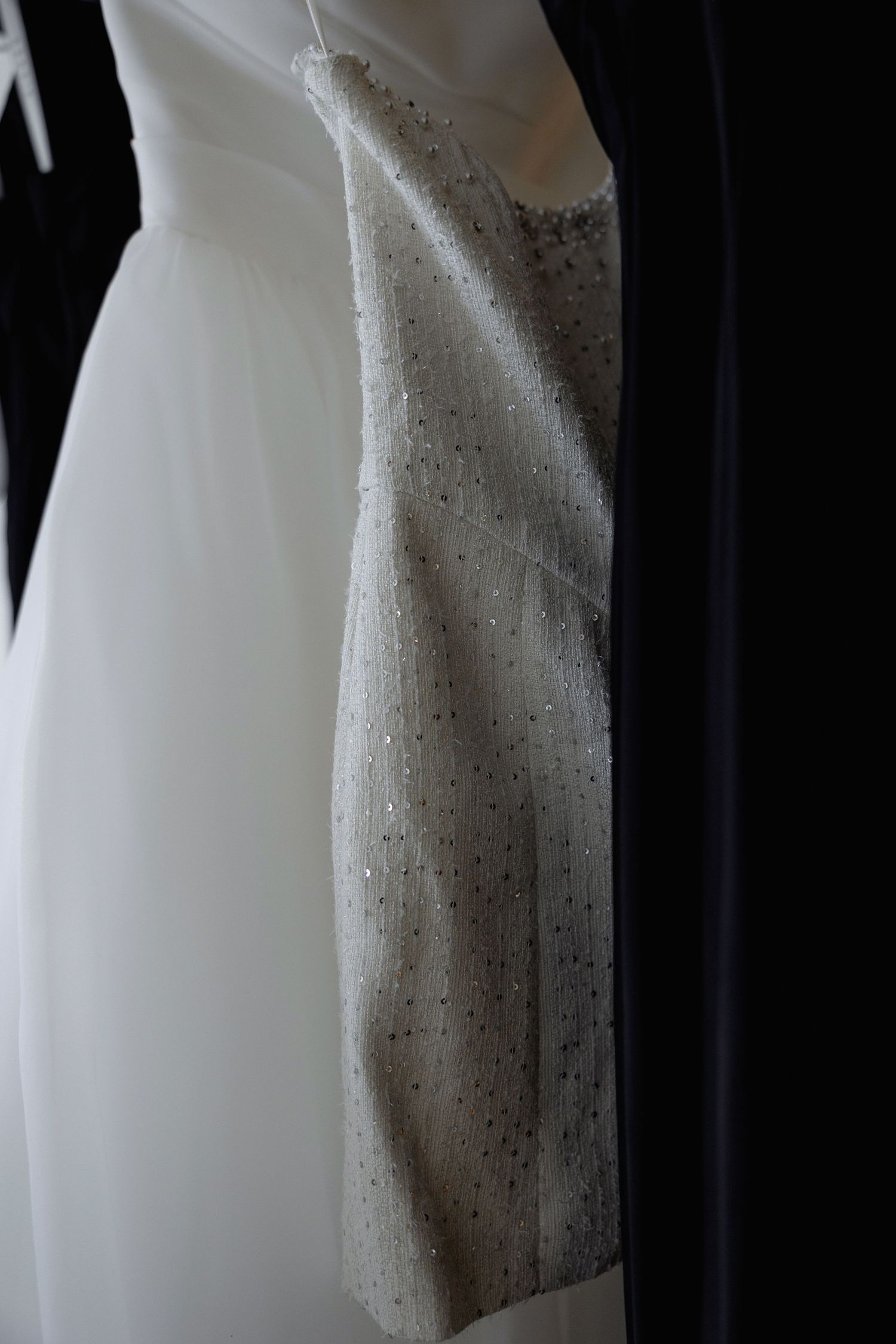Close-up detail of a white wedding dress with delicate beading and fabric texture.