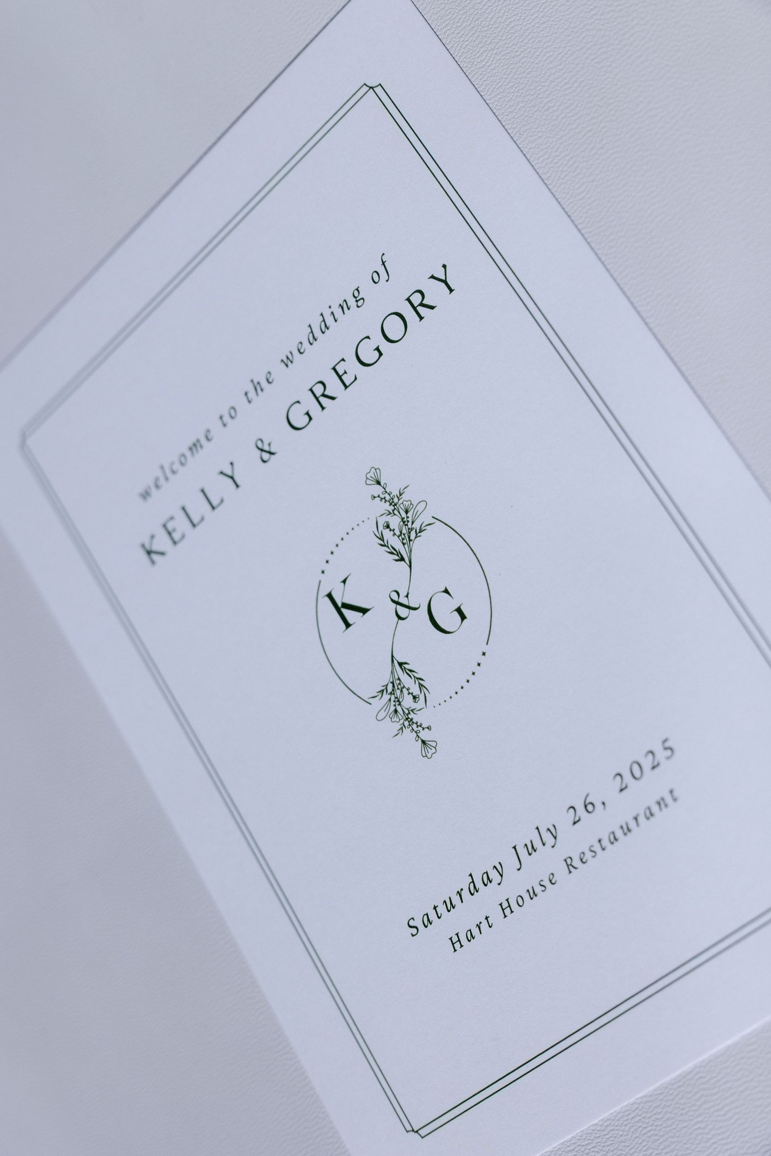 Minimalist wedding program with monogram design and botanical details on white paper.