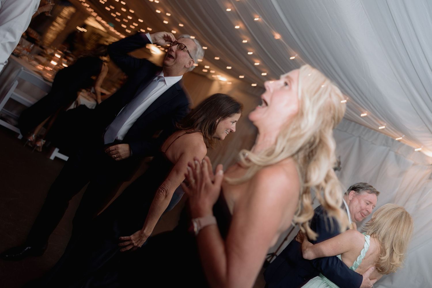 Guests dancing and celebrating at an evening wedding reception under string lights.