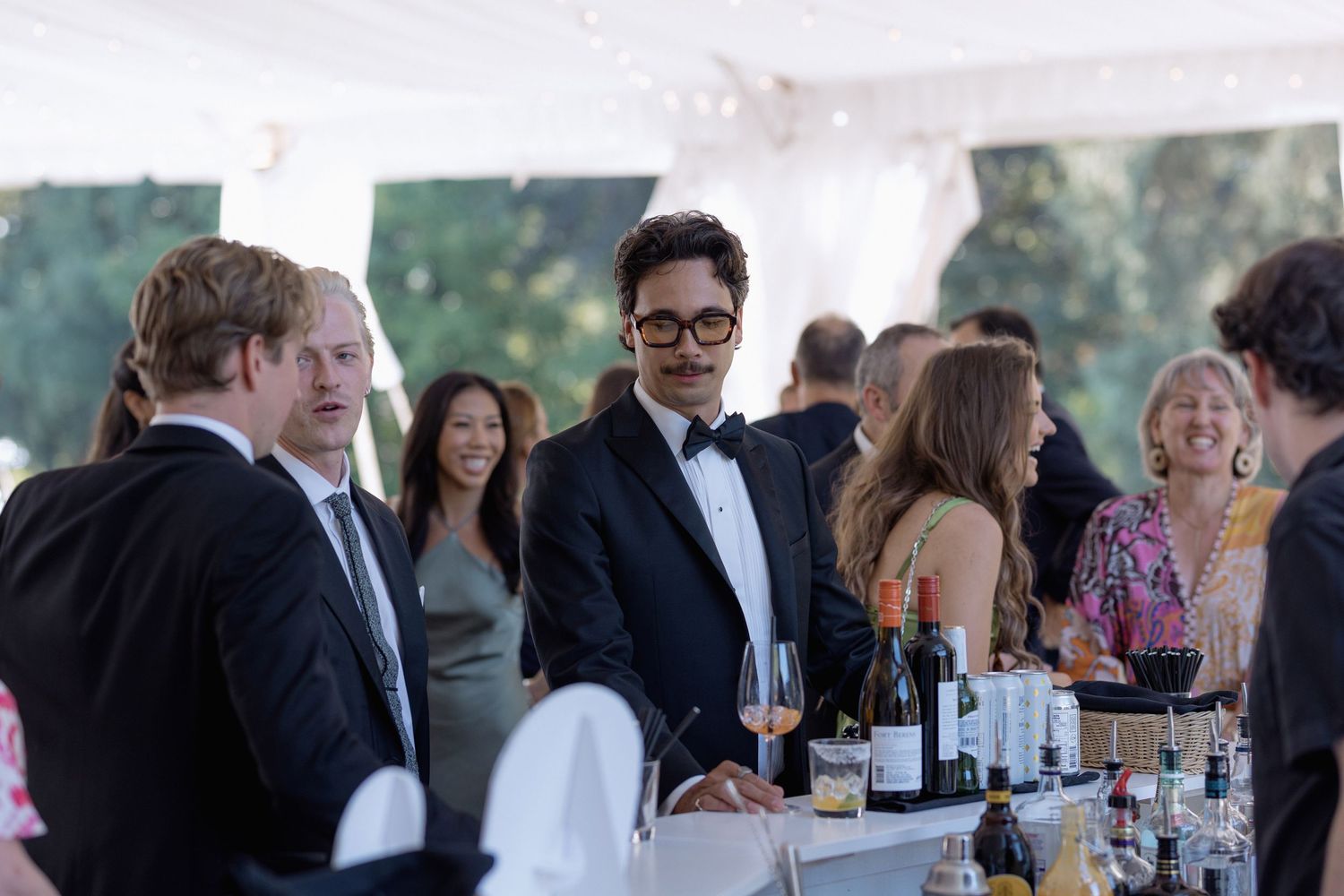 Guests socializing near a bar area at an elegant outdoor reception.