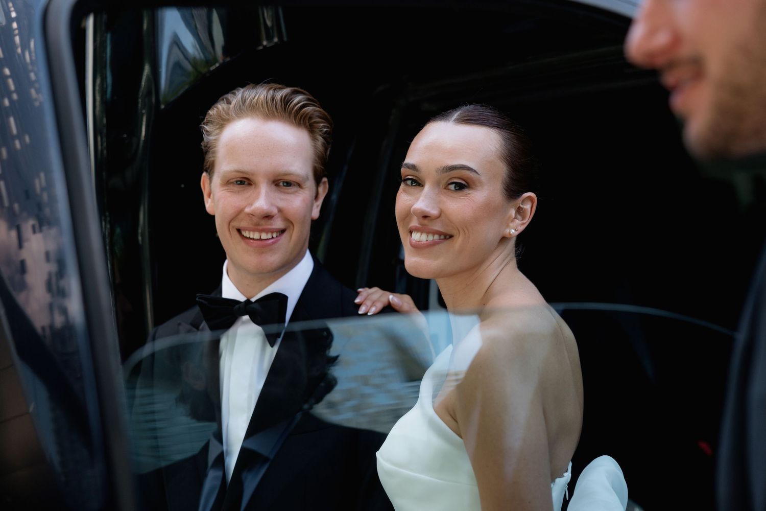 Candid moments captured between wedding party members near black vehicle.