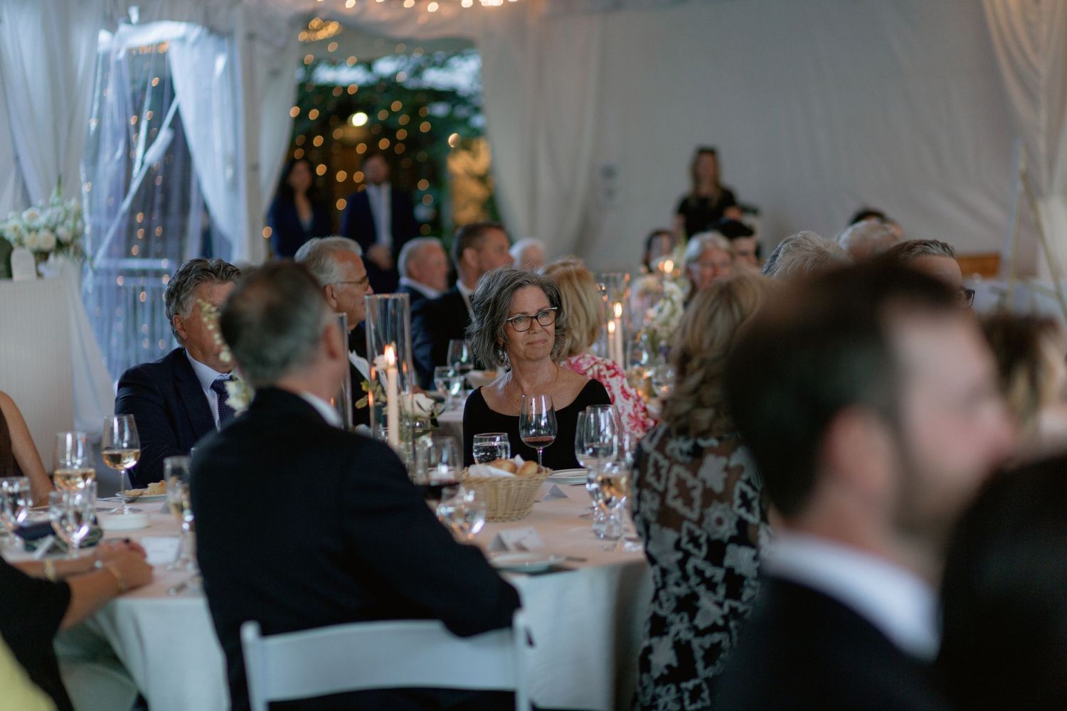 Wedding reception crowd watching entertainment in dimly lit tent venue.