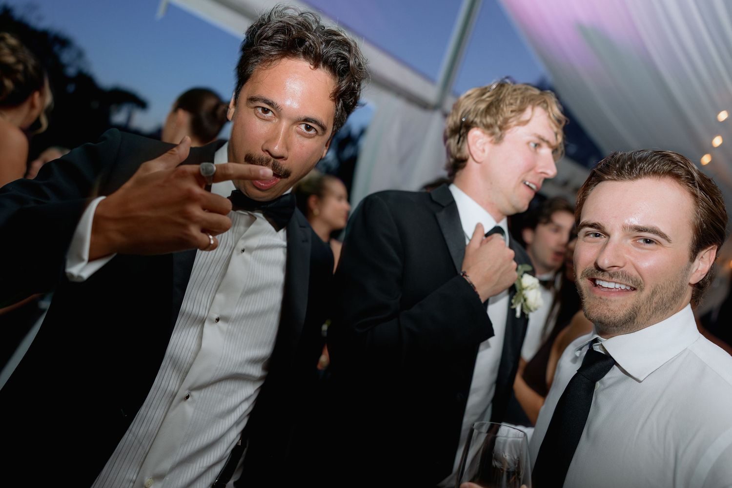 Wedding guests enjoying drinks and conversation during evening reception celebration.