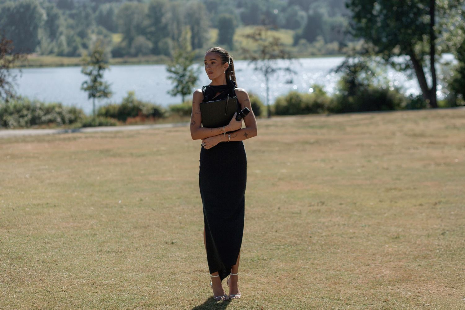 Grassy outdoor wedding venue with trees and natural landscape in background.