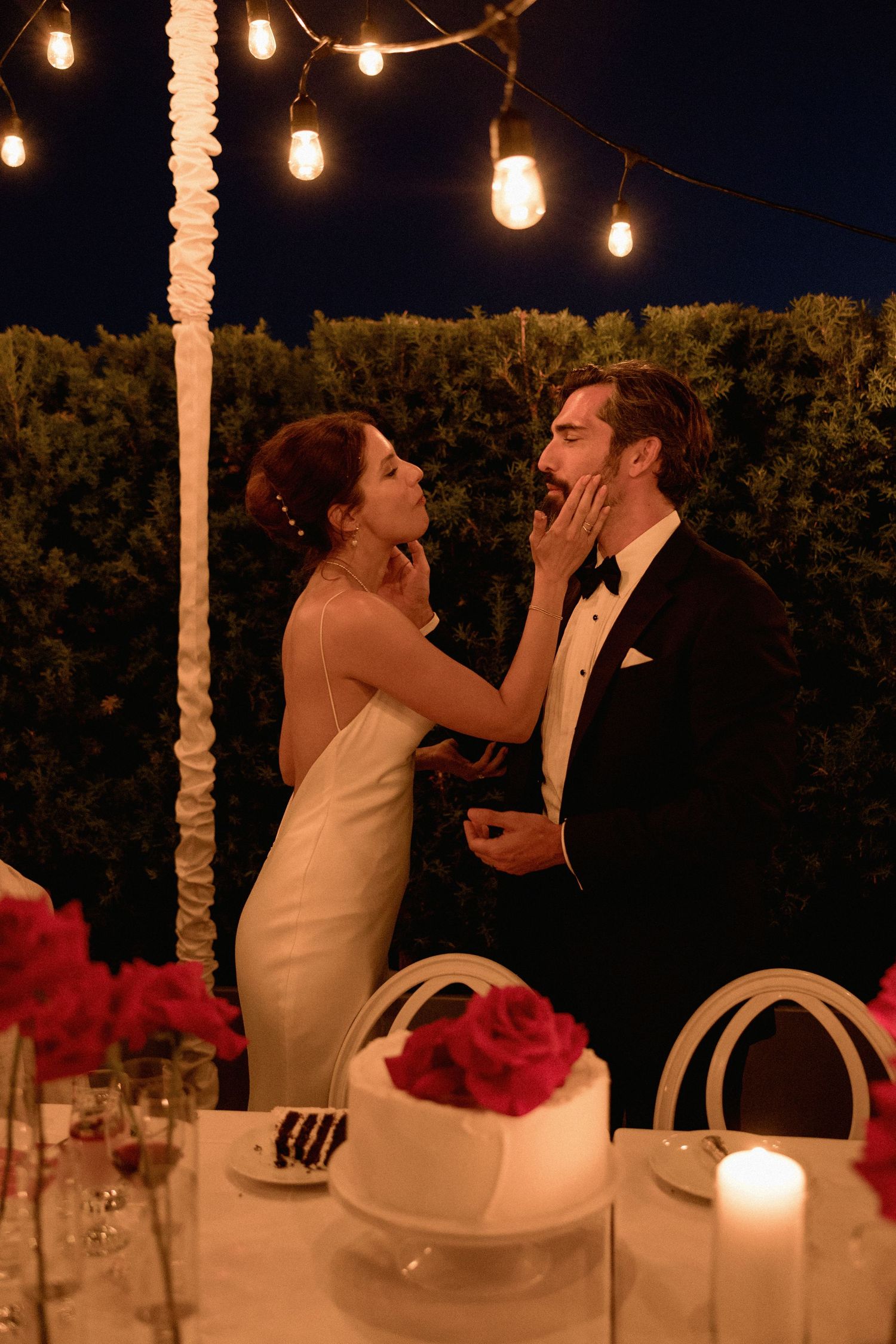 Intimate wedding moment under string lights with cake and table settings in Vancouver