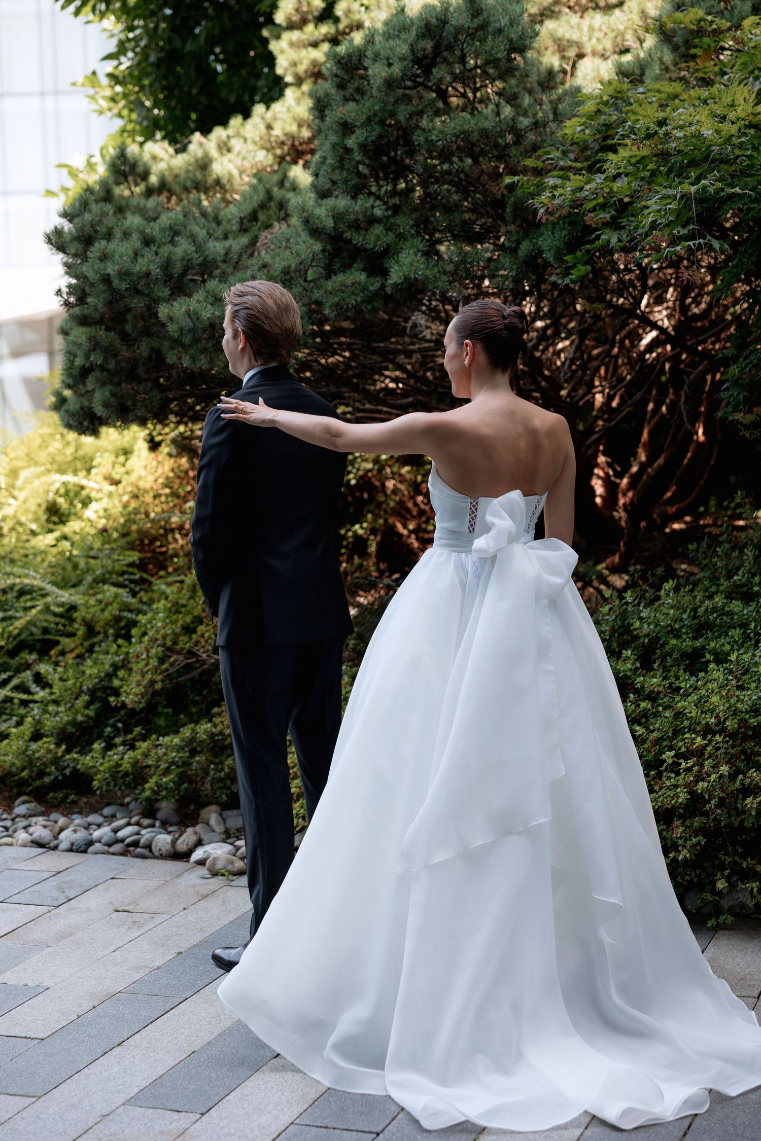 A first look wedding moment captured on a stone pathway surrounded by garden landscaping.