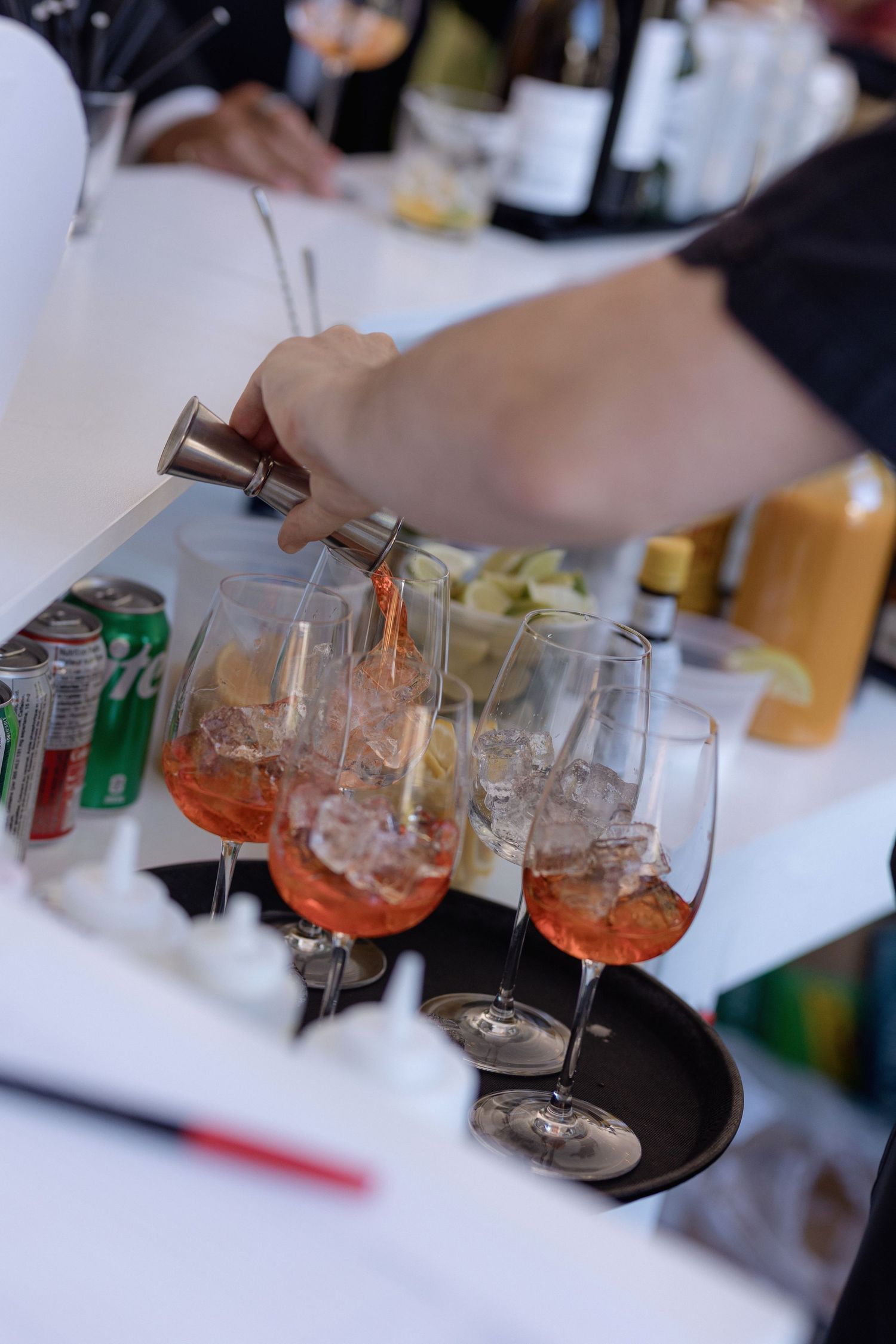 Bartender pouring orange cocktails into crystal glasses at an event bar.