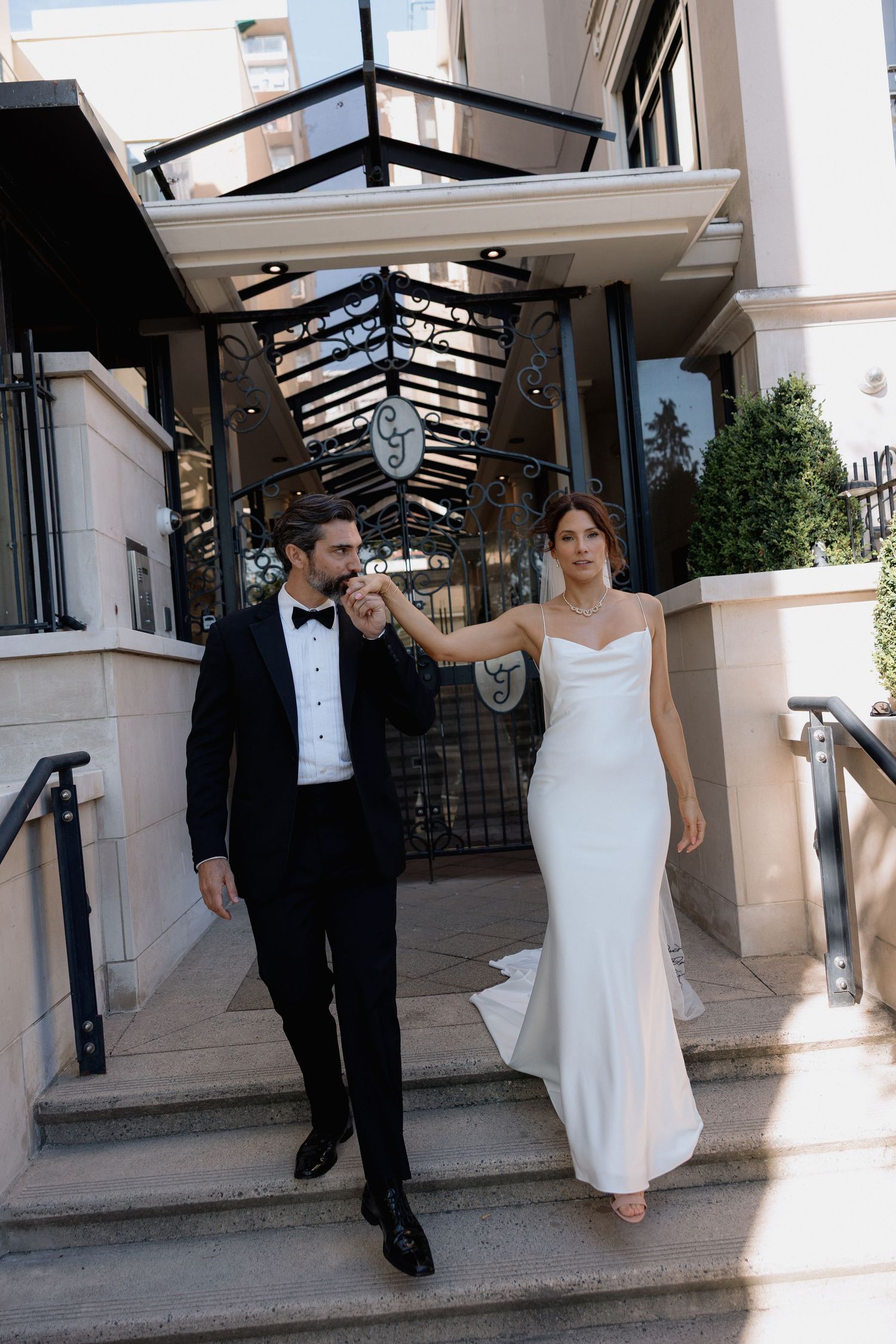 Couple walking down steps at venue entrance with glass ceiling and elegant decor.