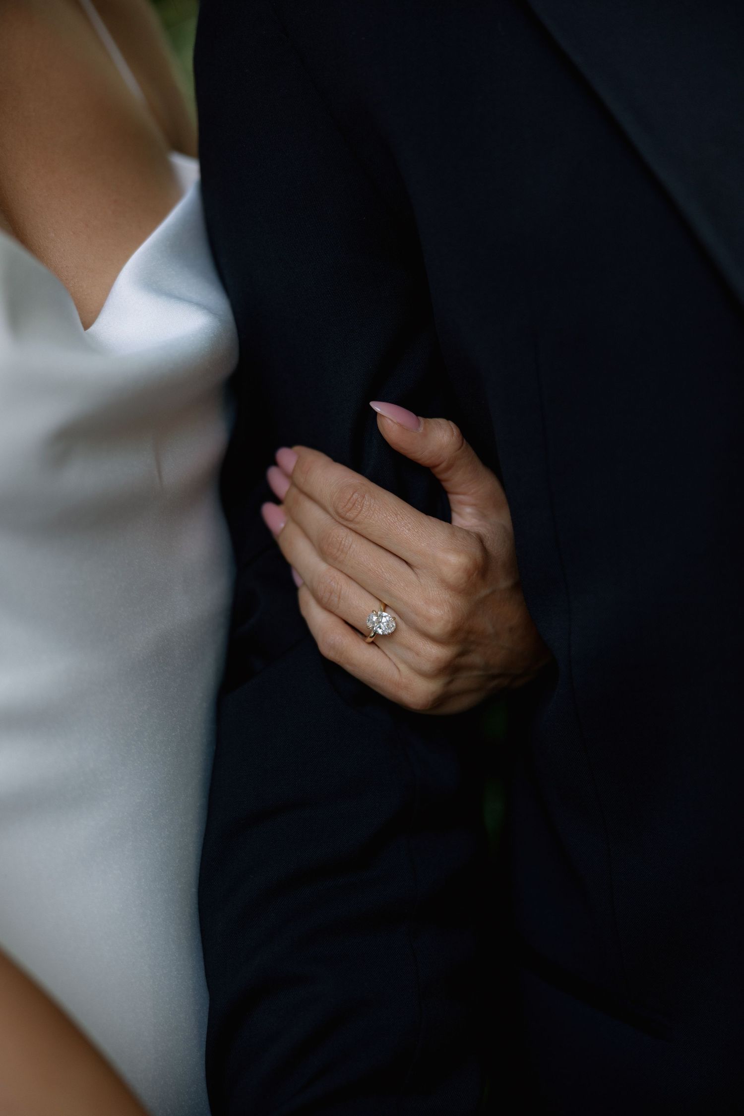 Close-up of hands showing wedding rings against black and white formal attire.