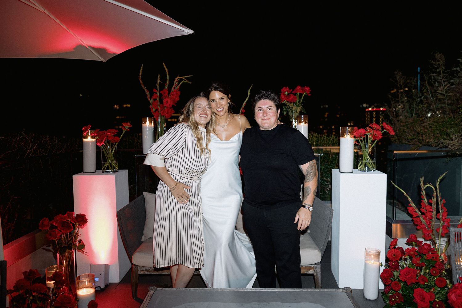 Wedding celebration on rooftop terrace with red floral decorations and white pillars in the night of Vancouver