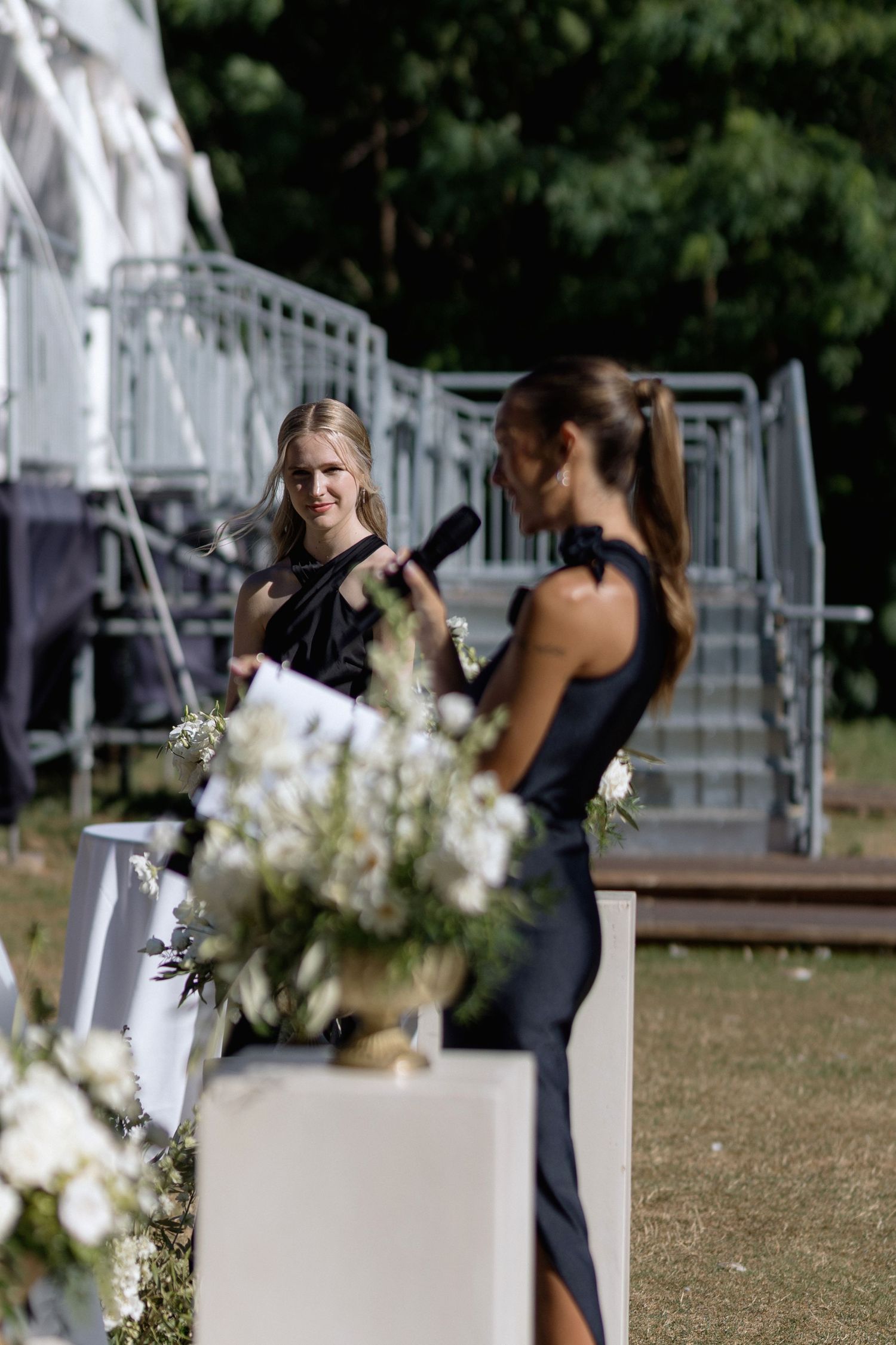 Wedding ceremony setup with white chairs and floral decorations in an outdoor venue.