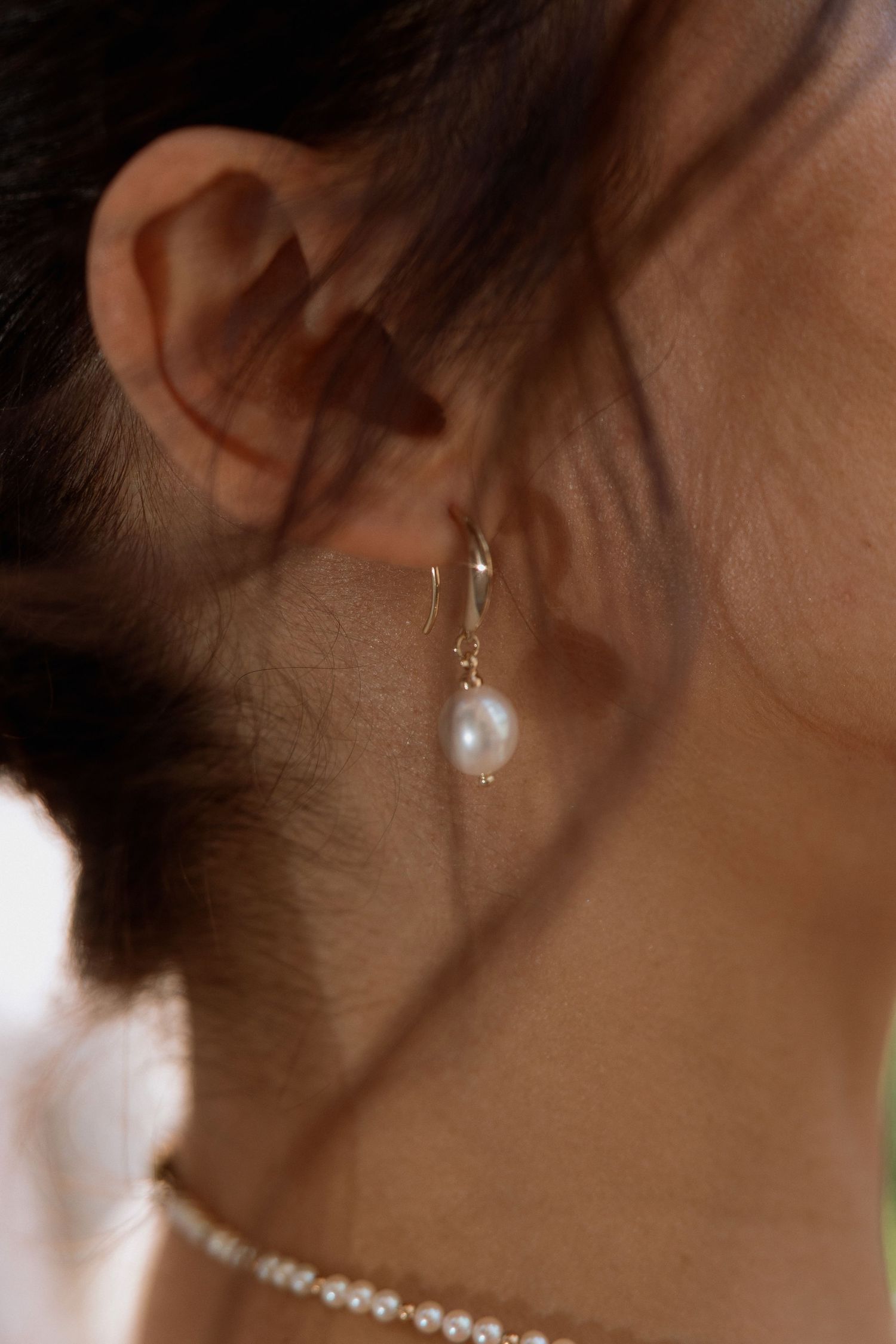 Close-up of a pearl drop earring against soft natural lighting.