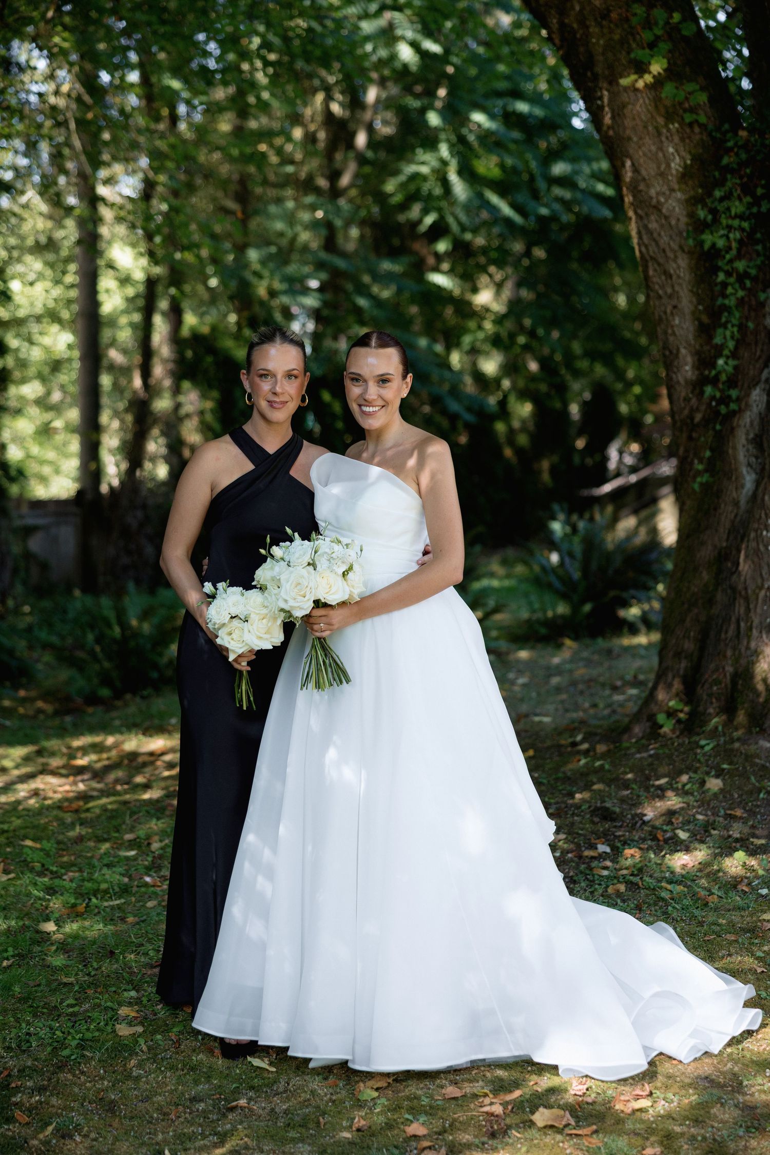 Elegant wedding portrait with two people in formal attire against a forest background.