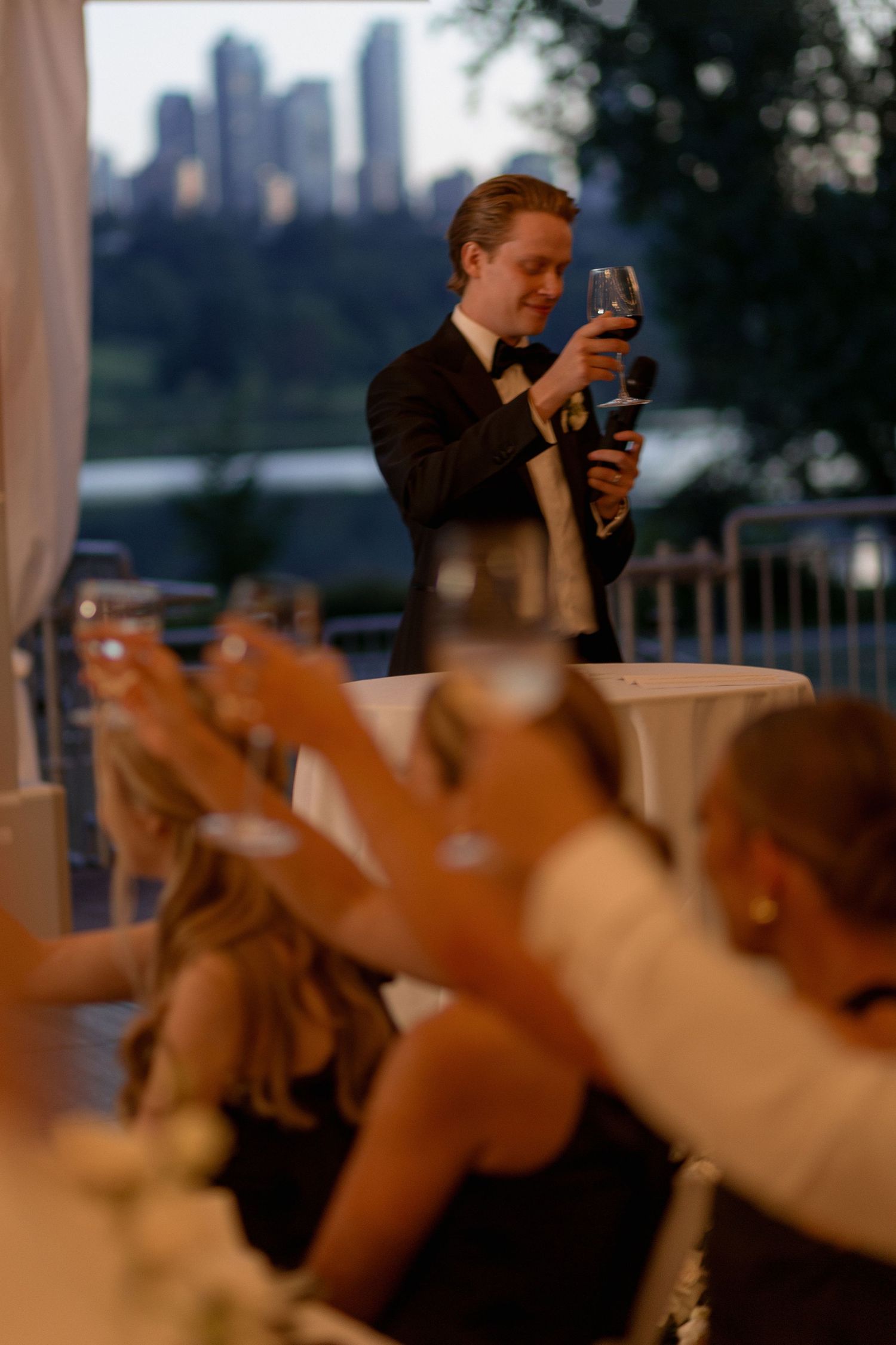 Wedding guests raising their glasses for a toast at an outdoor reception.