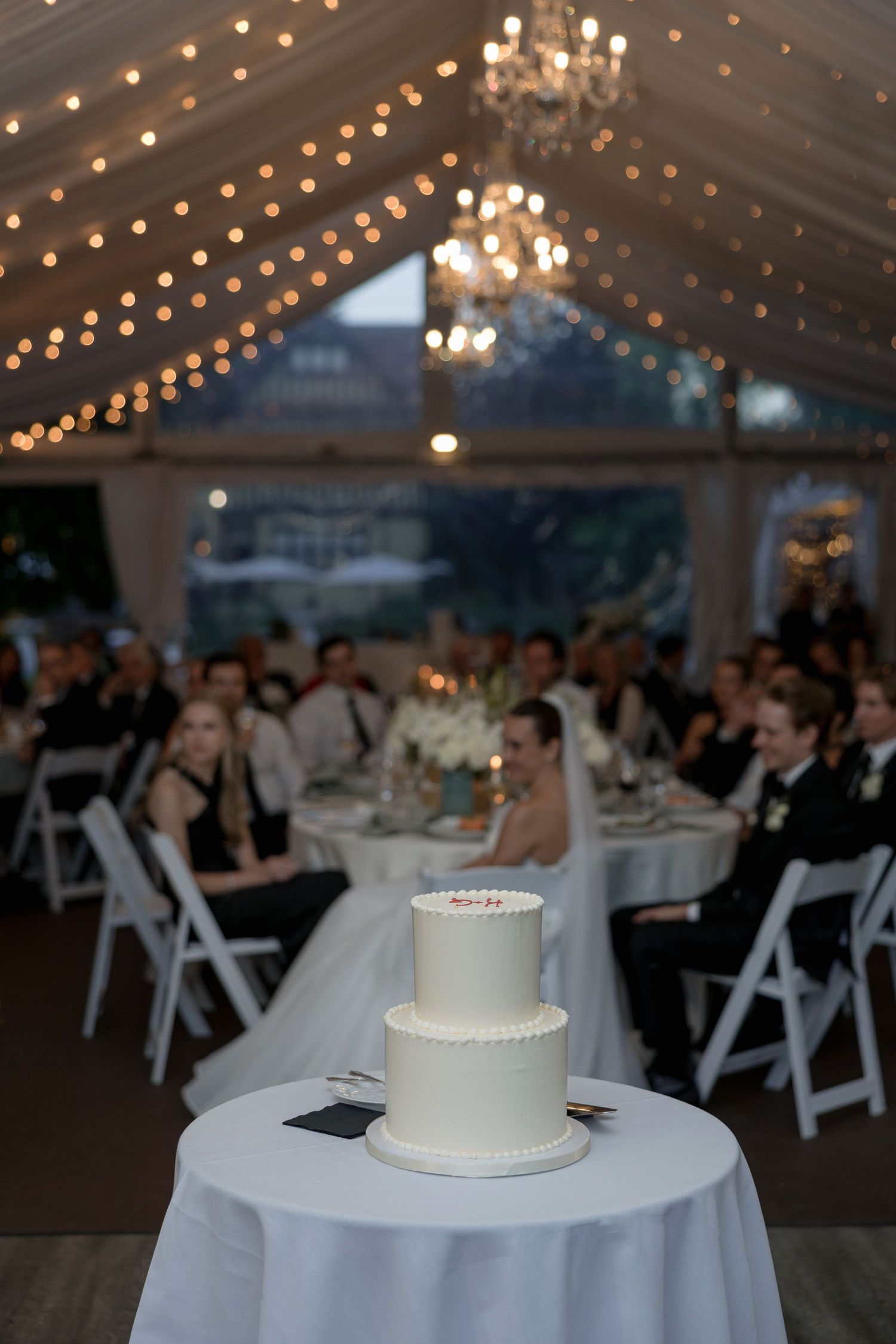 A wedding reception venue with white chairs and twinkling string lights hanging from the ceiling.