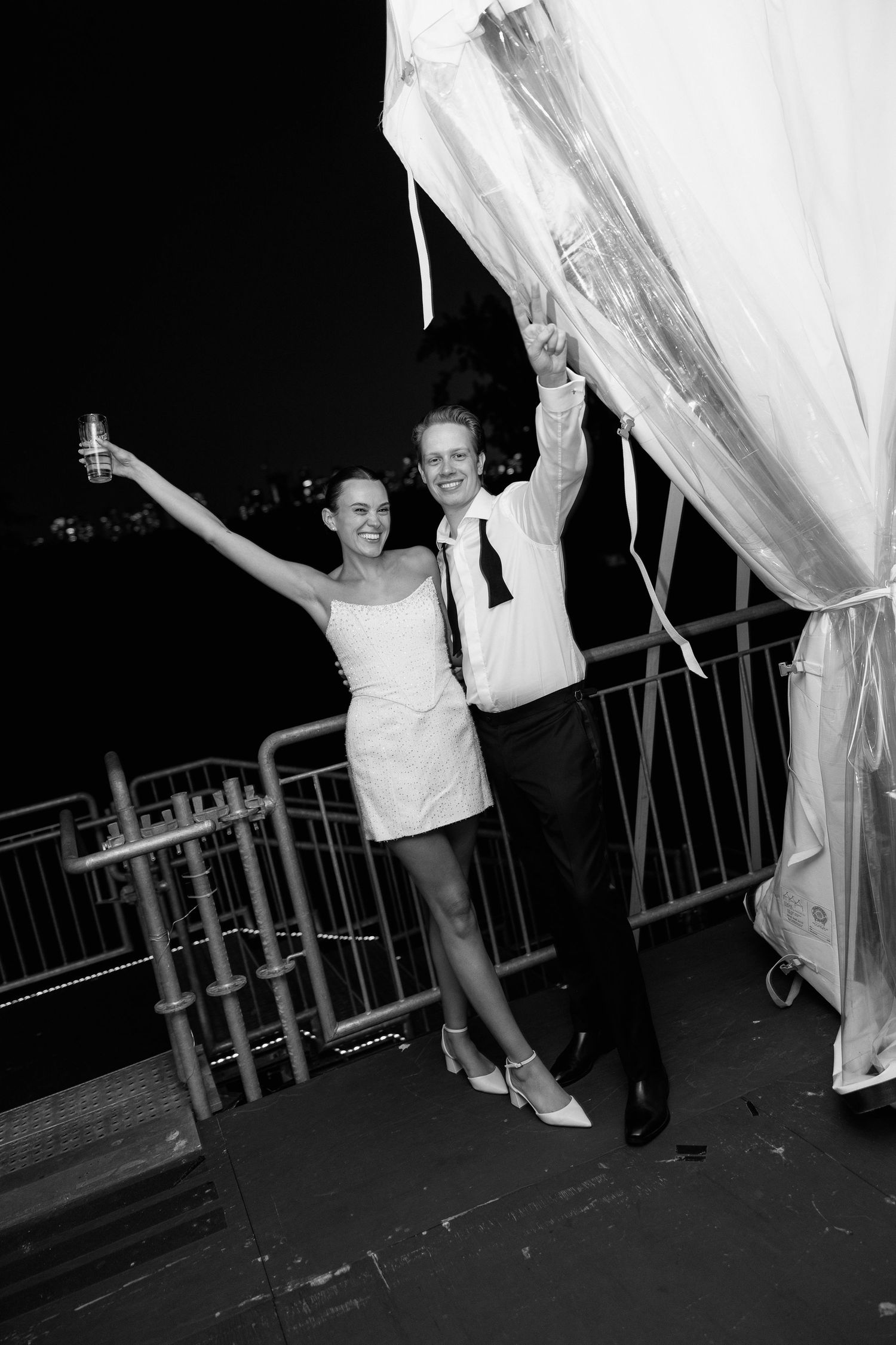 People celebrate with white curtains on an outdoor deck at night.