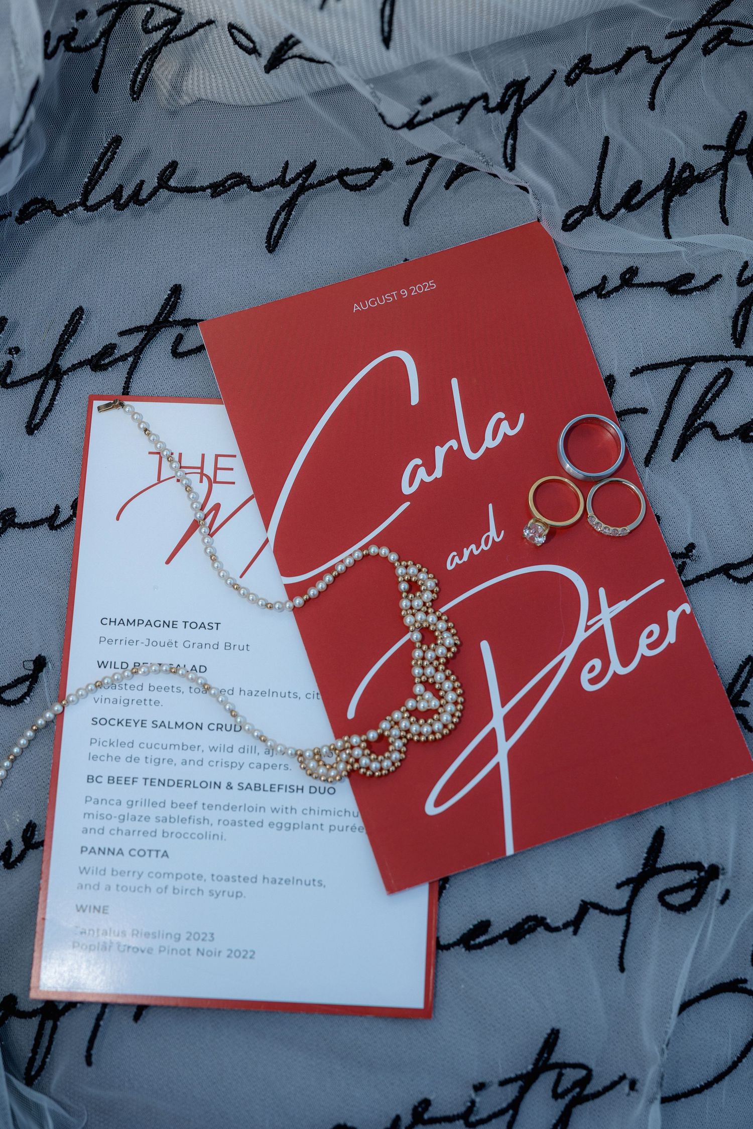 Red wedding invitation cards with elegant calligraphy displayed on a blue-tinted background with handwritten text.