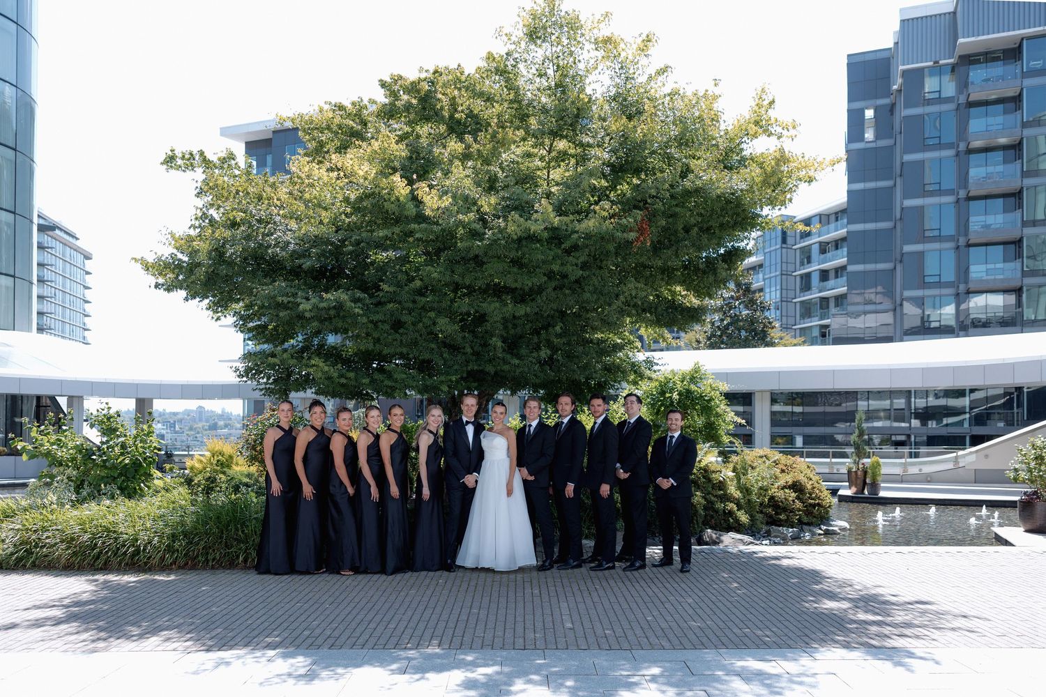 Wedding party lineup against urban backdrop with modern architecture and trees at Marriott Hotel in Vancouver