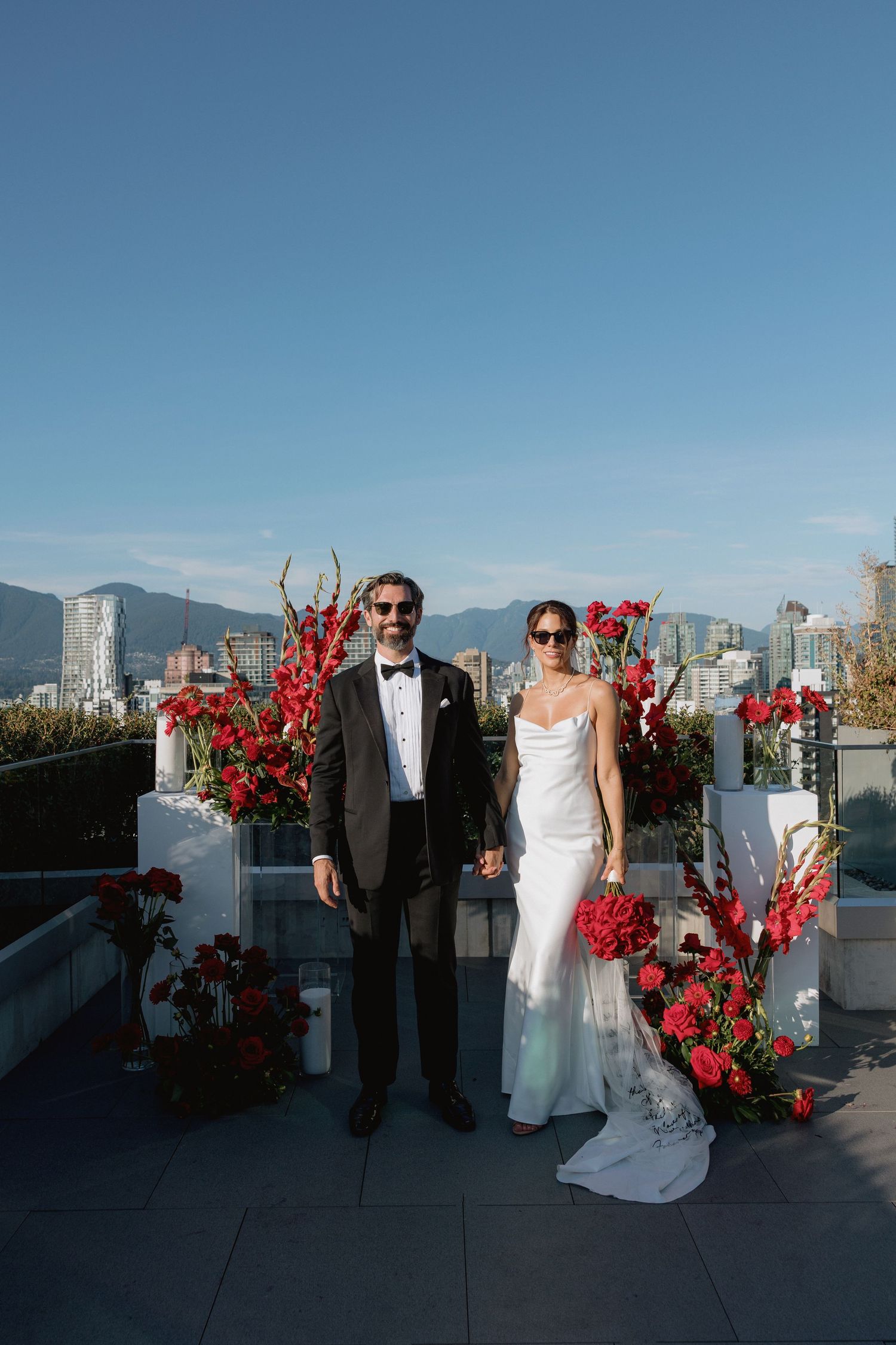 Rooftop wedding ceremony setup with red floral arrangements against Vancouver mountain backdrop.