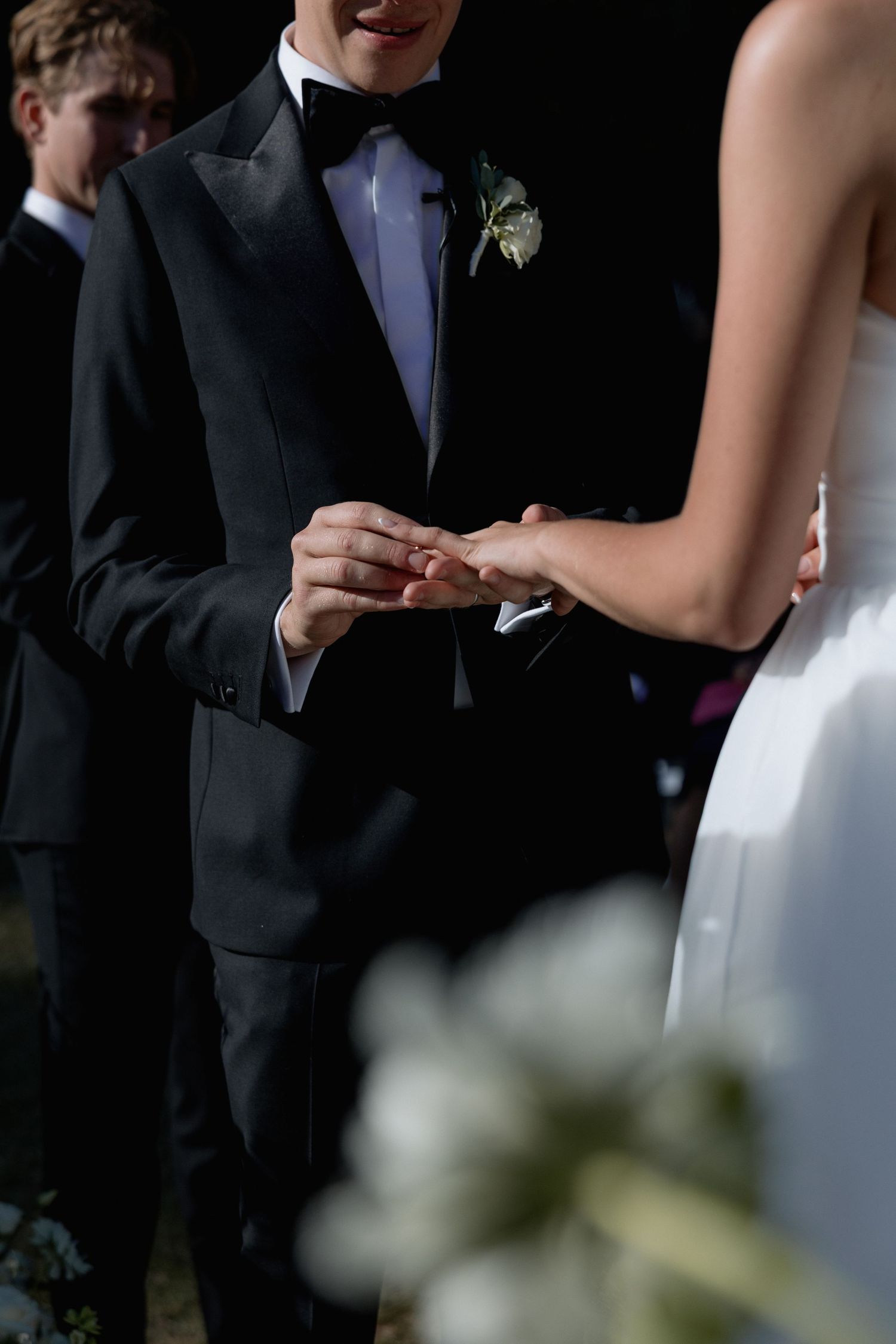 Close-up of wedding ceremony showing formal attire and exchanging of rings.