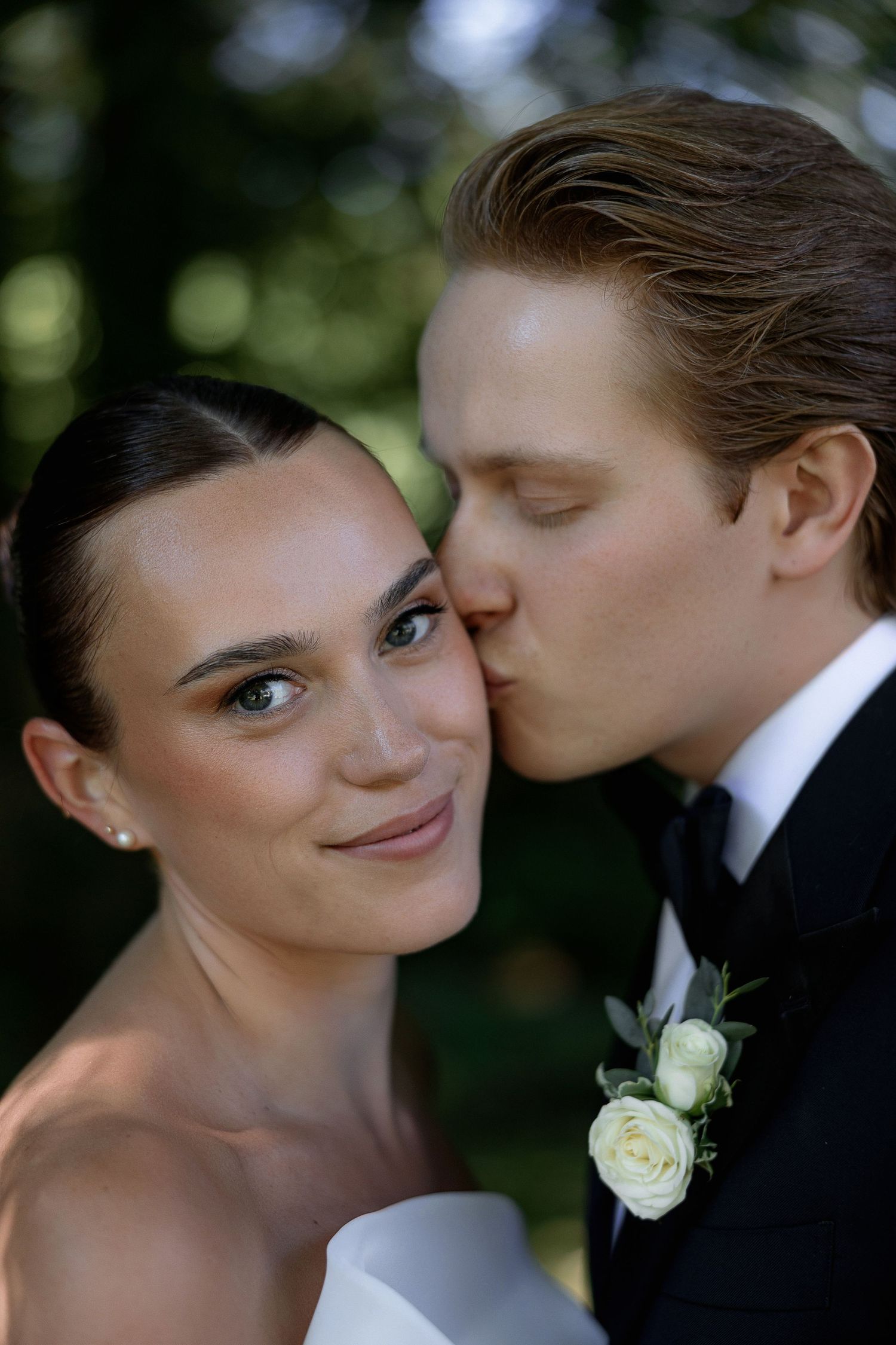 Close-up wedding portraits capturing sweet moments between the couple against natural greenery.