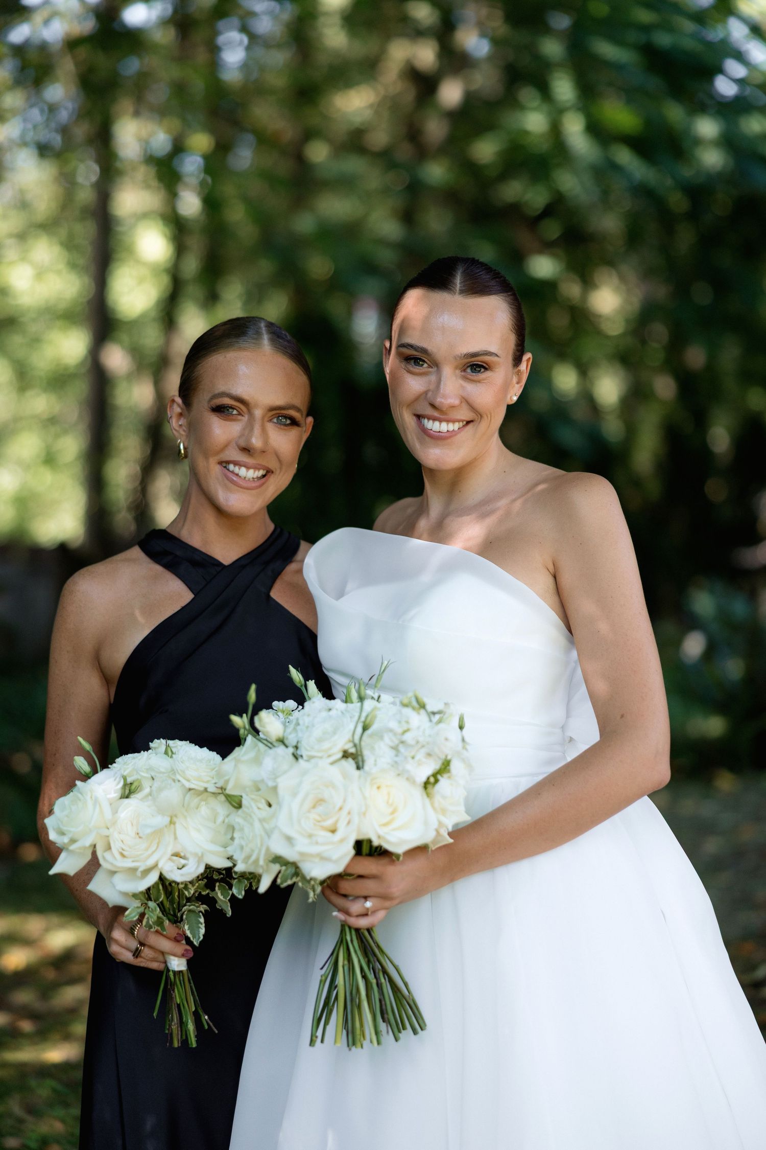 Close up portrait of two people at a wedding with white roses and forest backdrop.