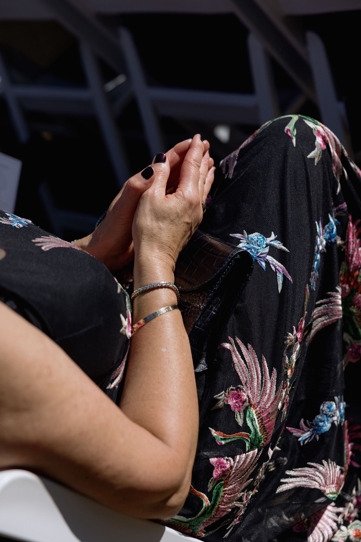 Close-up of a black dress with colorful floral embroidery patterns.