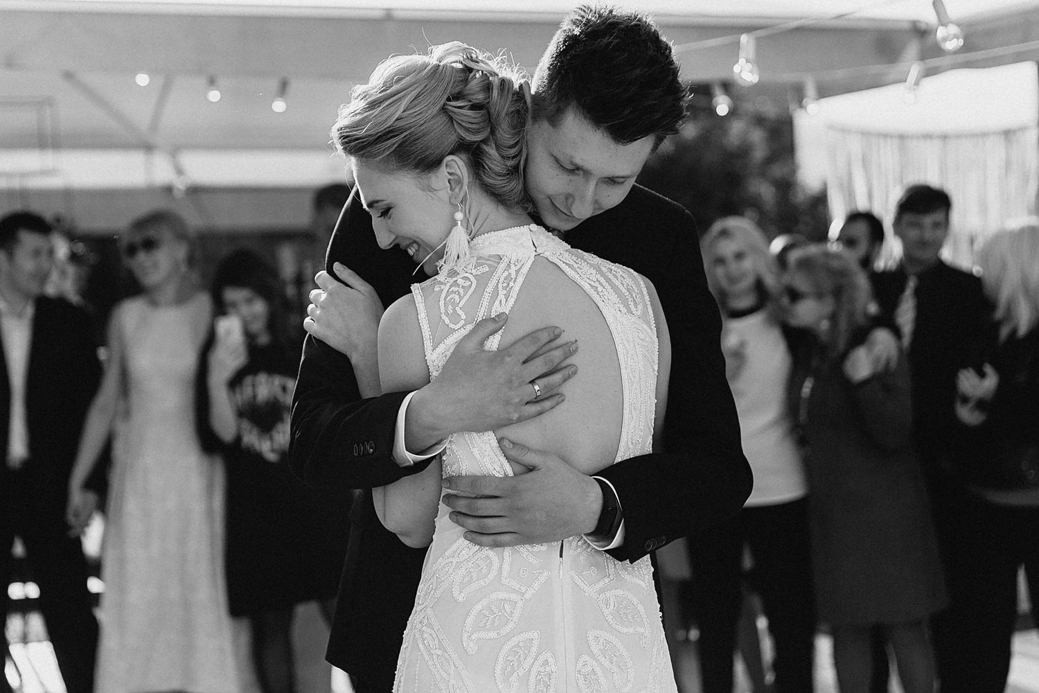 Wedding reception dance under string lights in black and white.