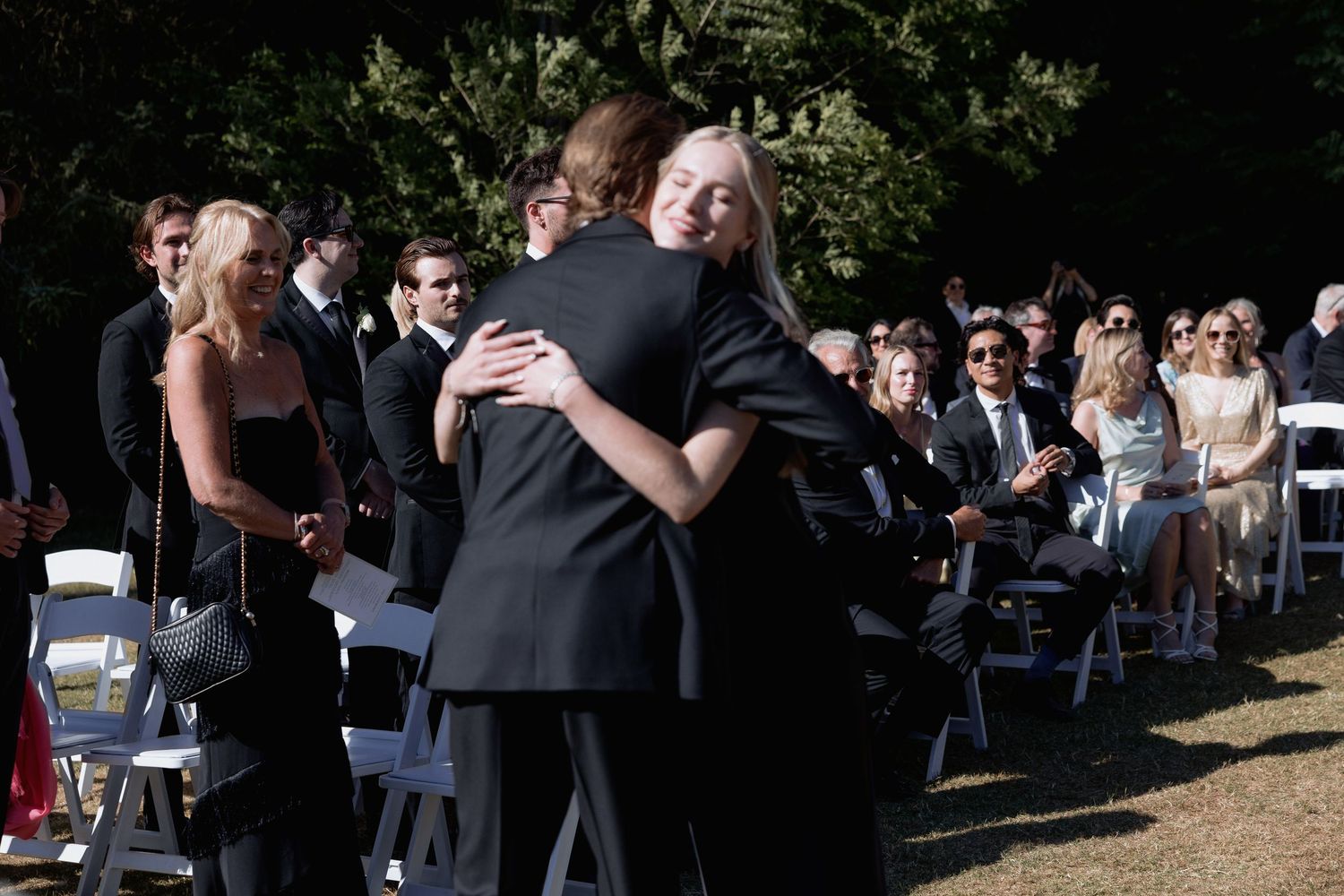 Wedding celebration in progress with guests embracing during an outdoor ceremony.