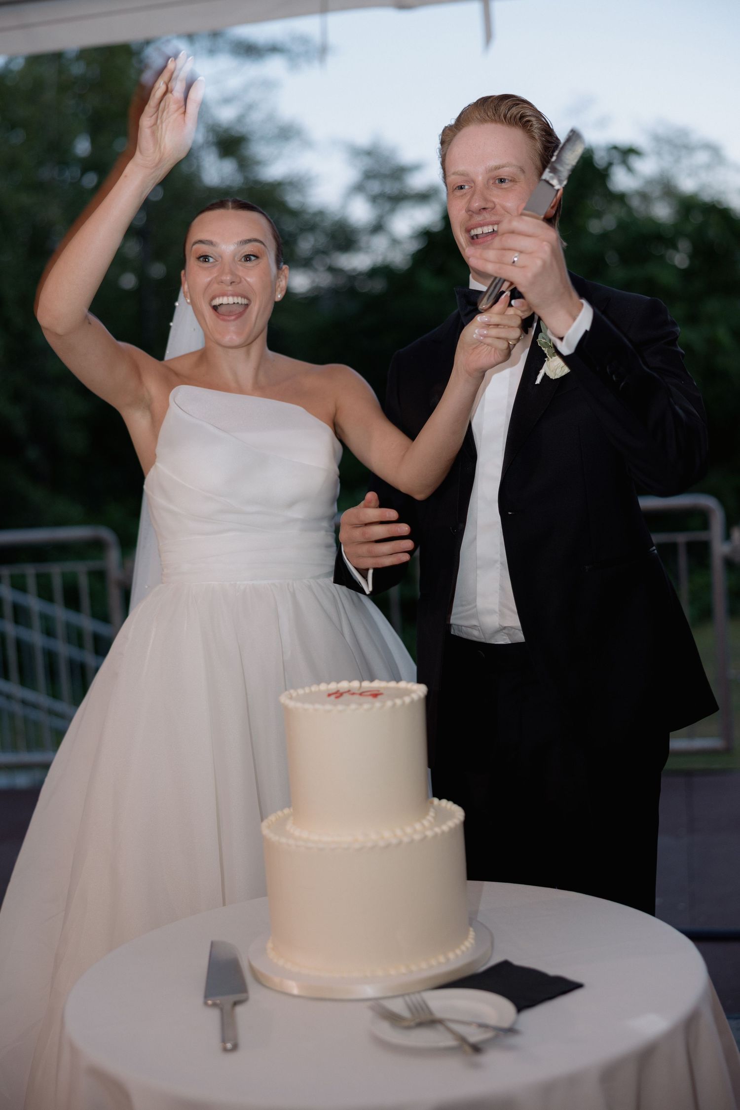 A joyful moment during a wedding cake viewing on an outdoor terrace.