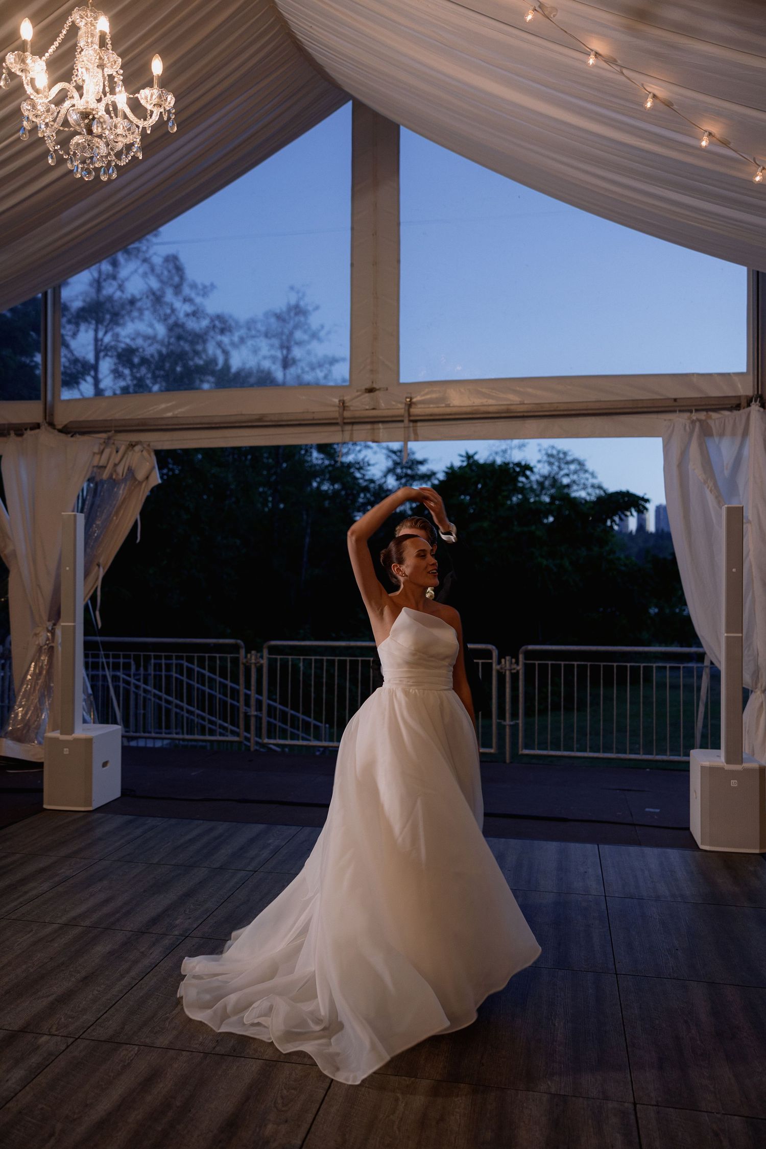 Couple sharing a romantic dance under an elegant white tent at twilight.