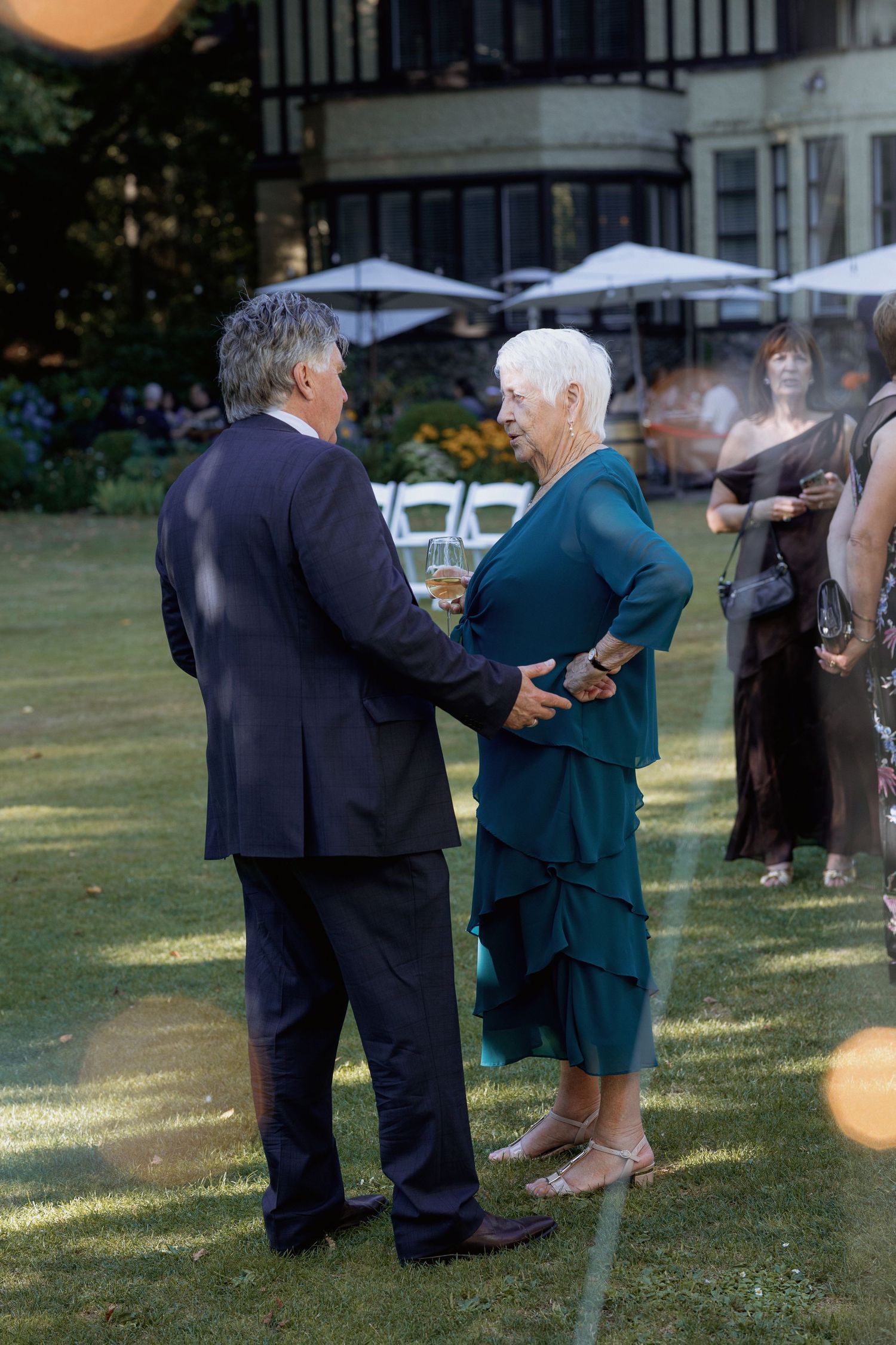 Guests dancing at an outdoor wedding reception on a grassy lawn.