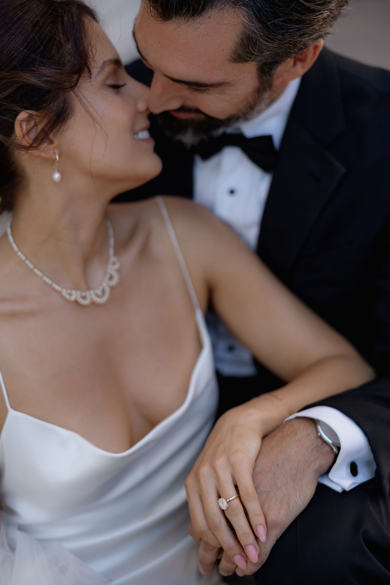 Close-up romantic wedding photos showing tender moments between a couple in formal attire with jewelry details.