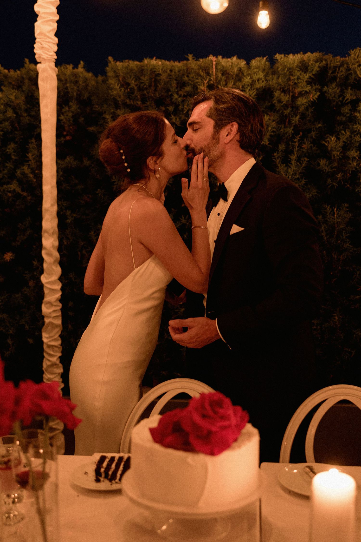 Couple shares intimate moment at candlelit reception table decorated with pink flowers in Vancouver