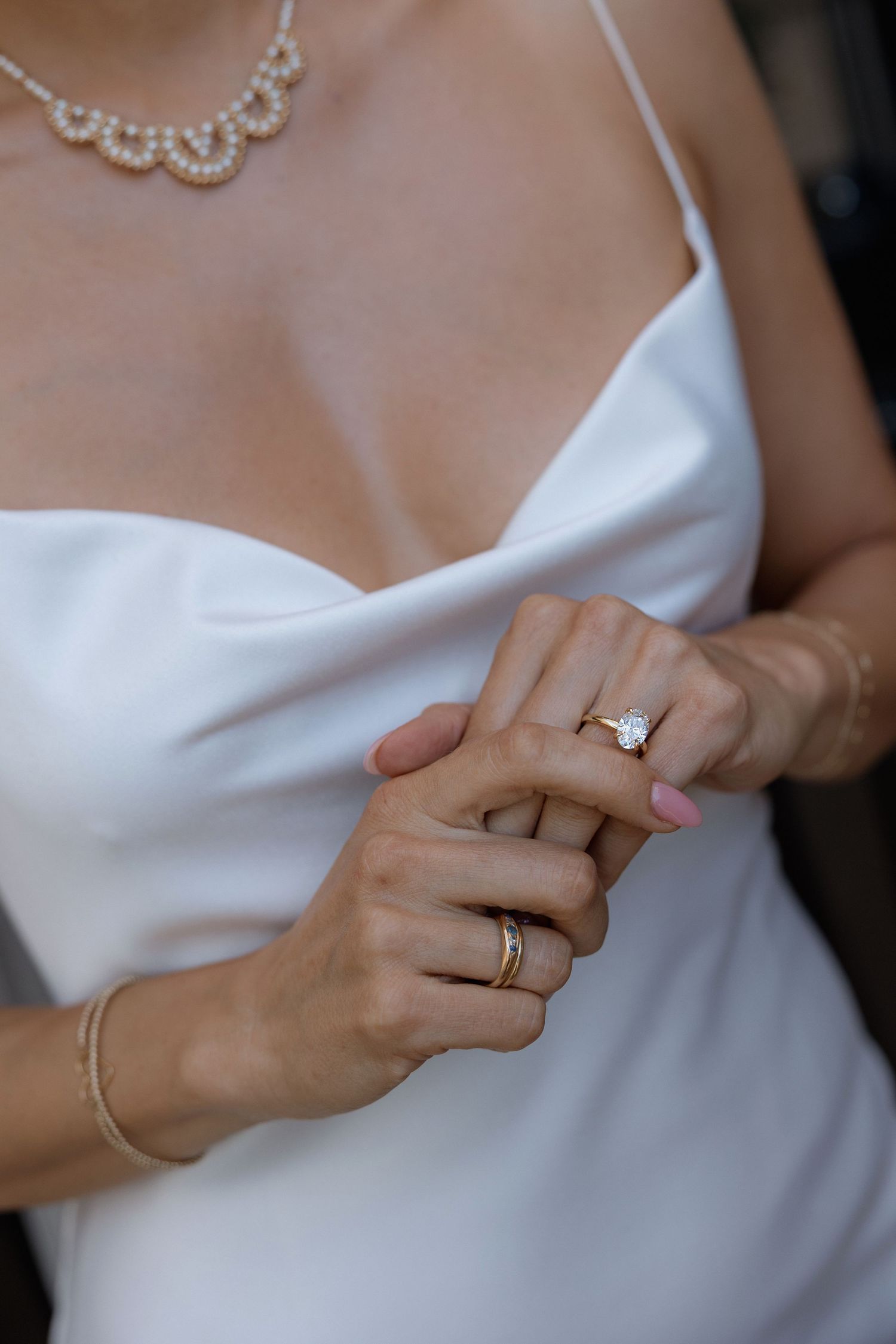 Close-up of bride's hands showing elegant engagement and wedding rings.