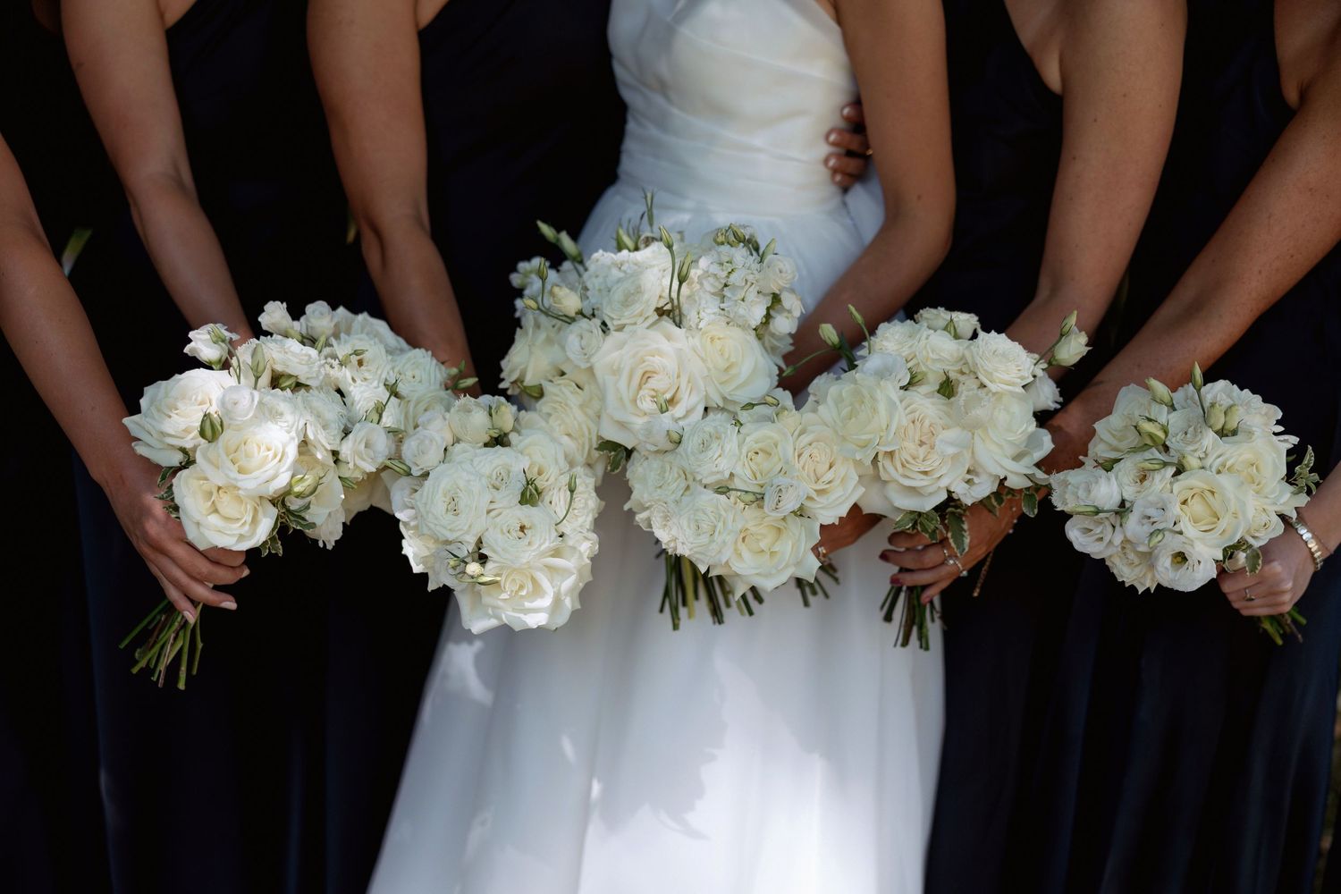 Close-up of white floral bouquets held by wedding party members.