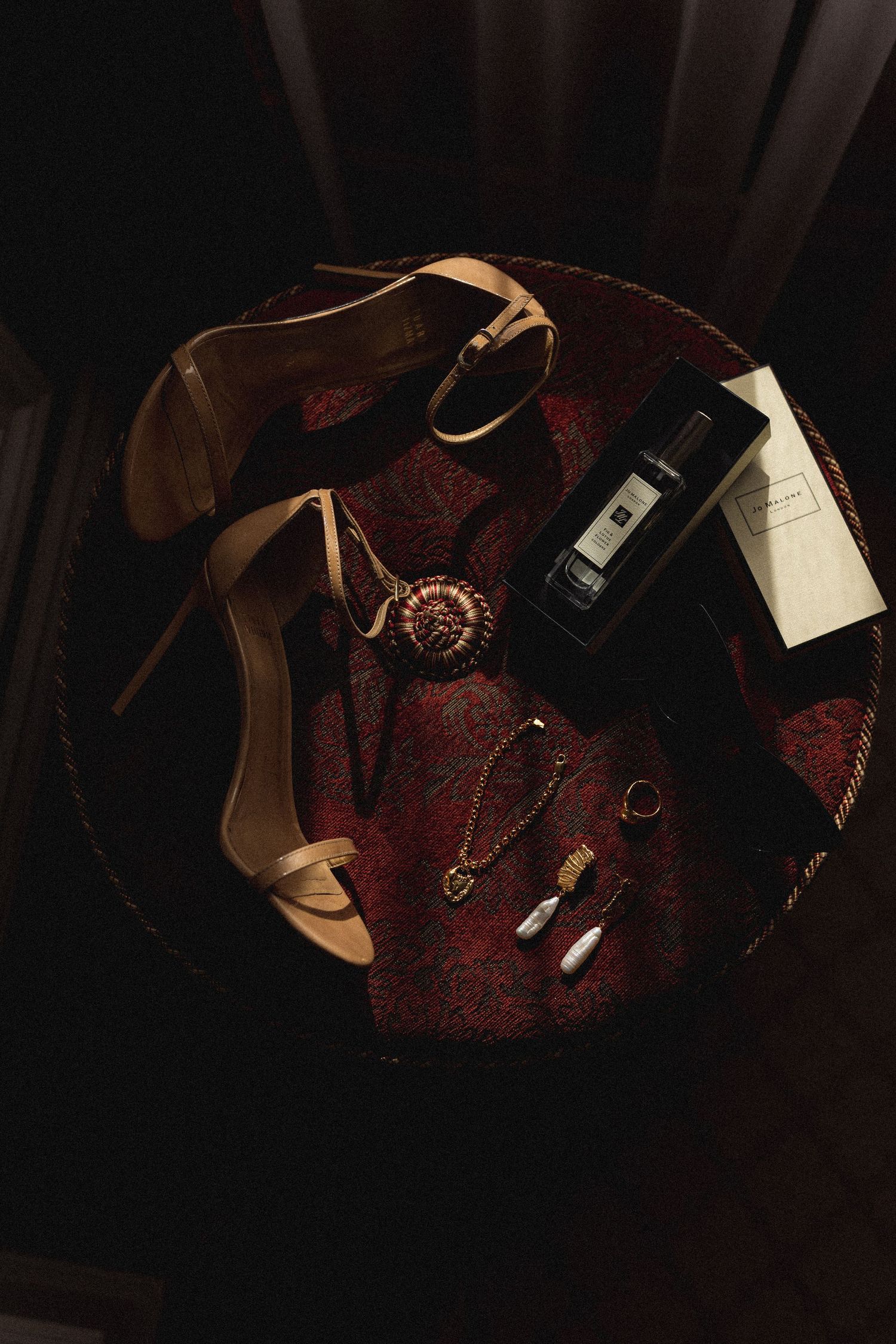 Dark moody flatlay of wedding accessories and details on burgundy velvet.