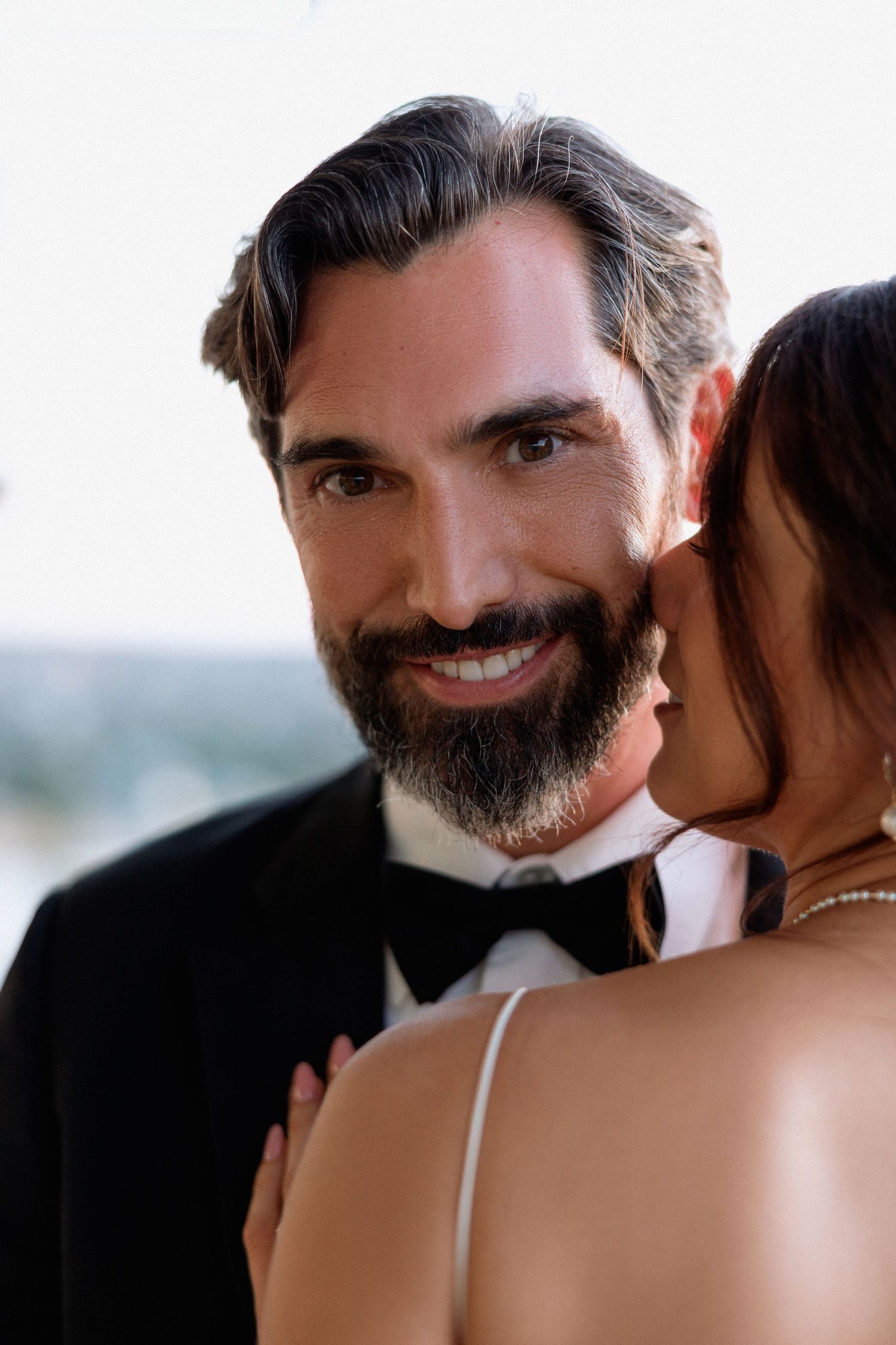 A romantic close-up series of a bearded man in black suit and bride in white dress sharing intimate moments.