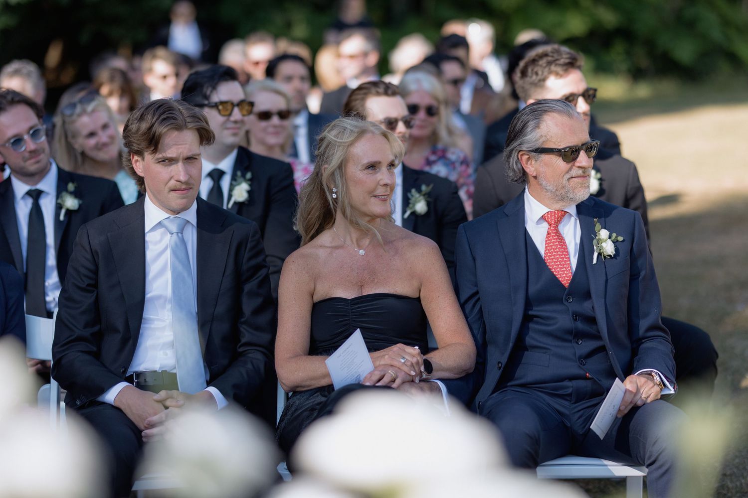 Wedding guests seated in formal attire watching the outdoor ceremony.