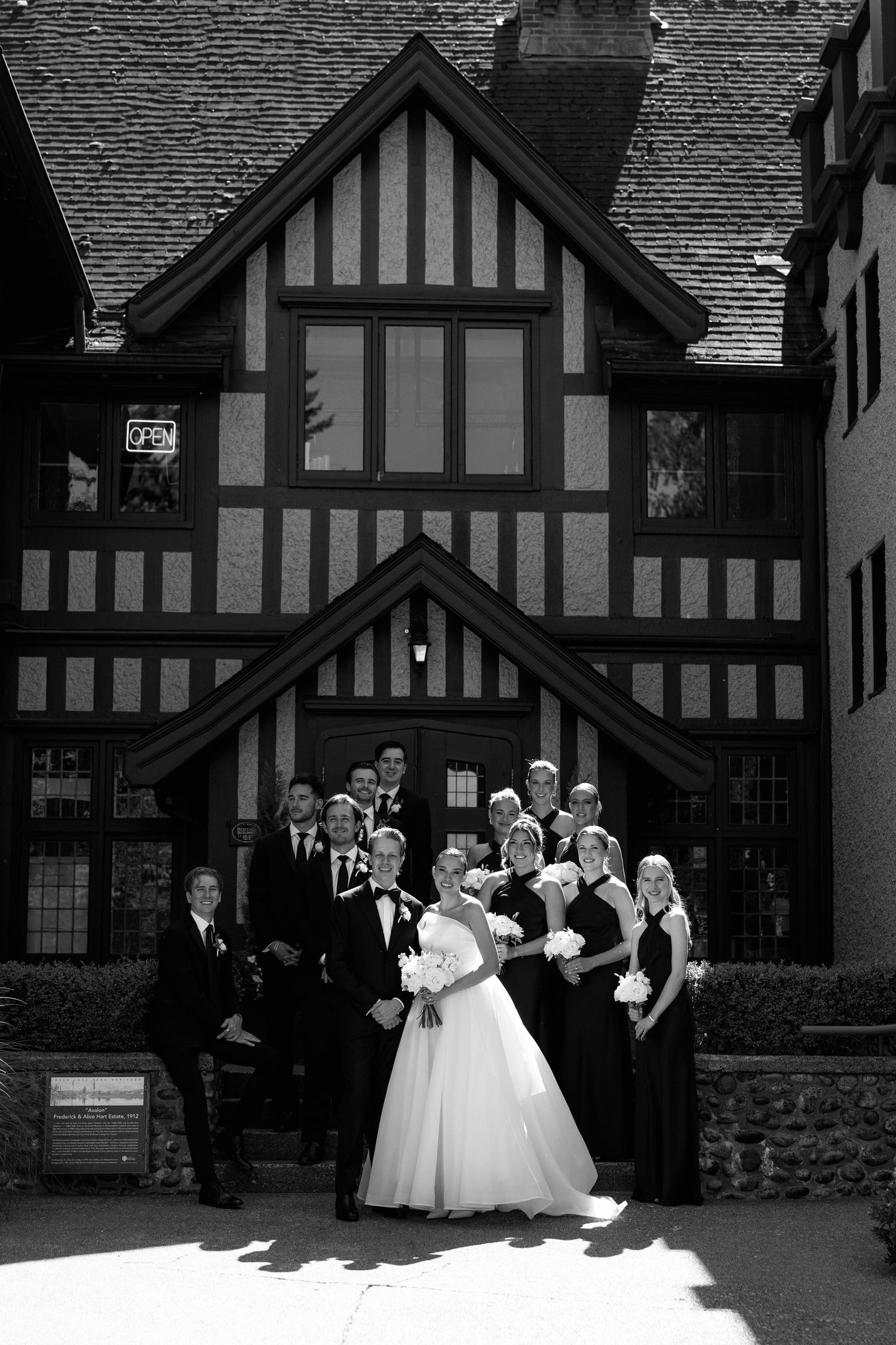 Black and white wedding party portrait in front of Tudor-style architecture at Hurt House in Burnaby